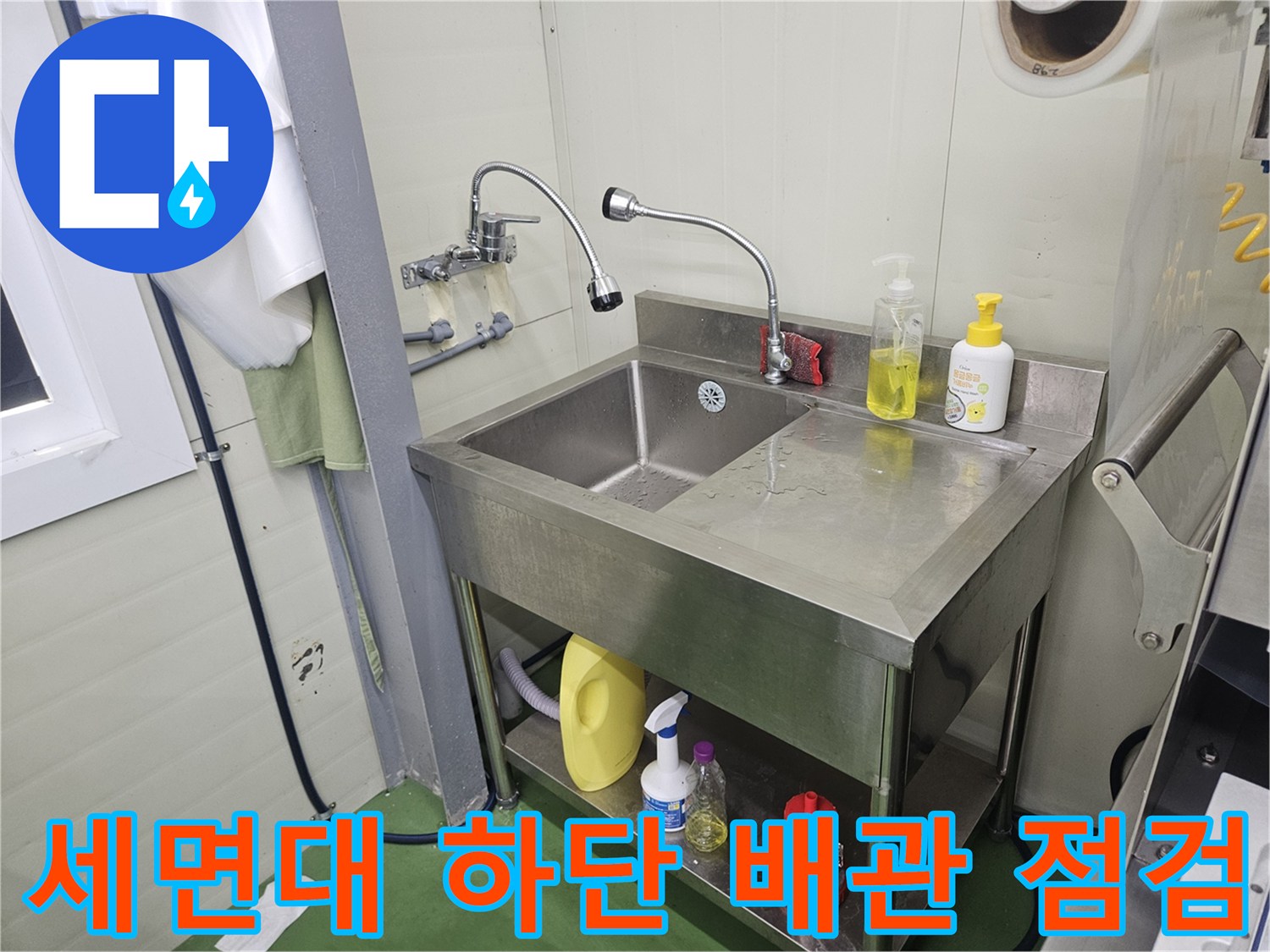 화장실 세면대 아래쪽 배관 연결 부위와 스테인리스 선반 모습