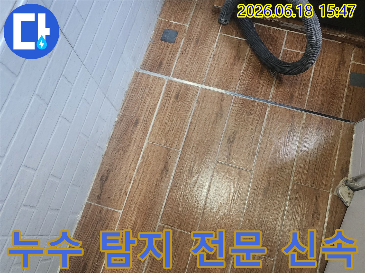 염창동 아파트에서 누수 탐지 전문가가 정확하고 신속하게 작업을 진행 중인 현장 사진입니다-바닥 타일 위에 검은색 호스가 놓여 있습니다.