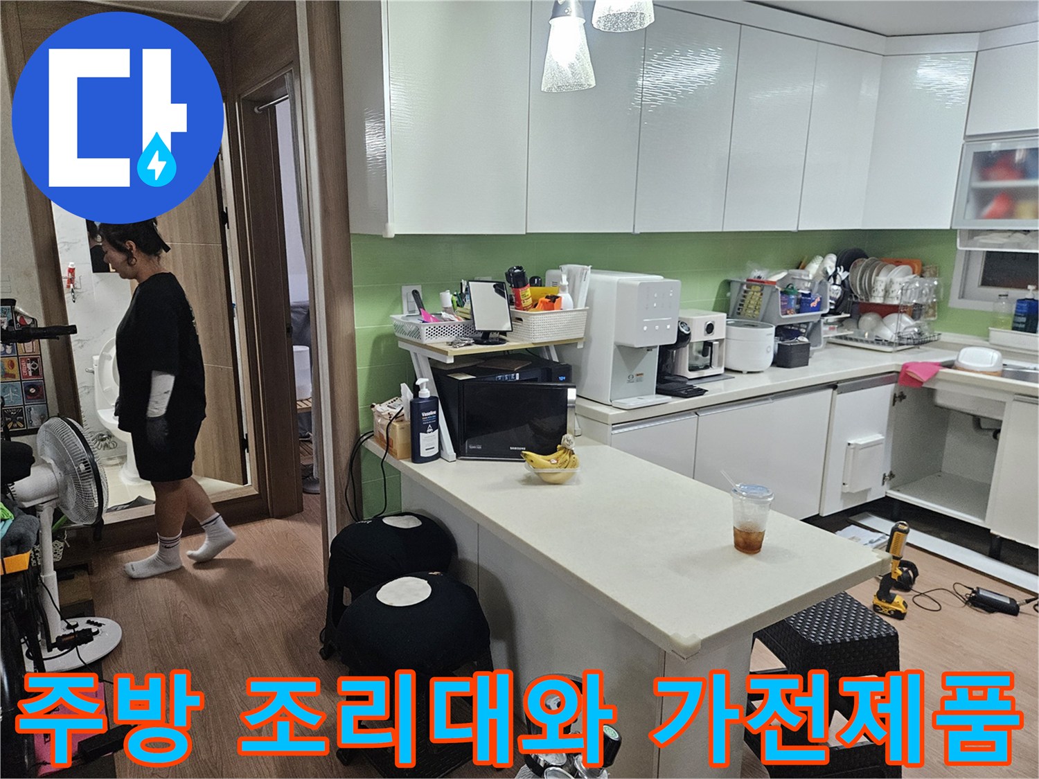 싱크대 상판 위에 놓인 커피머신과 전자레인지가 있는 주방 풍경입니다.