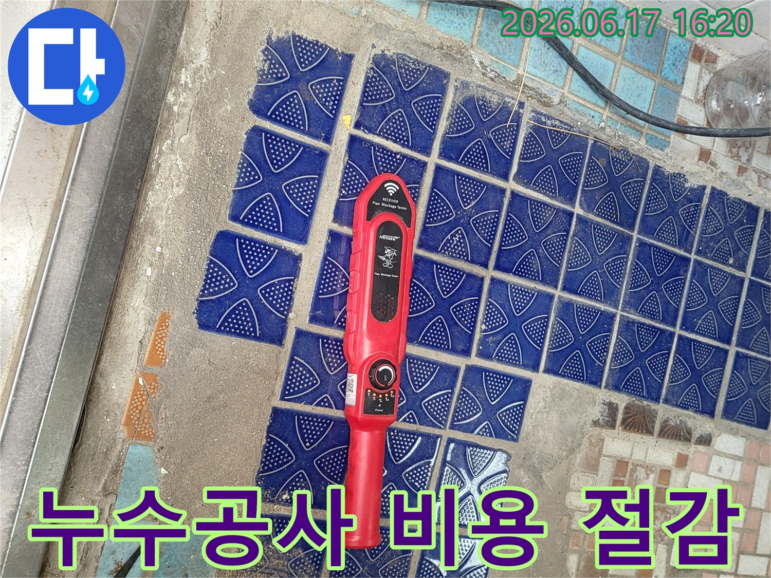 파란색 타일이 부분적으로 제거된 욕실 바닥에-붉은색 누수탐지 장비가 놓여-정확한 탐지로 공사 비용을 절감하는 모습