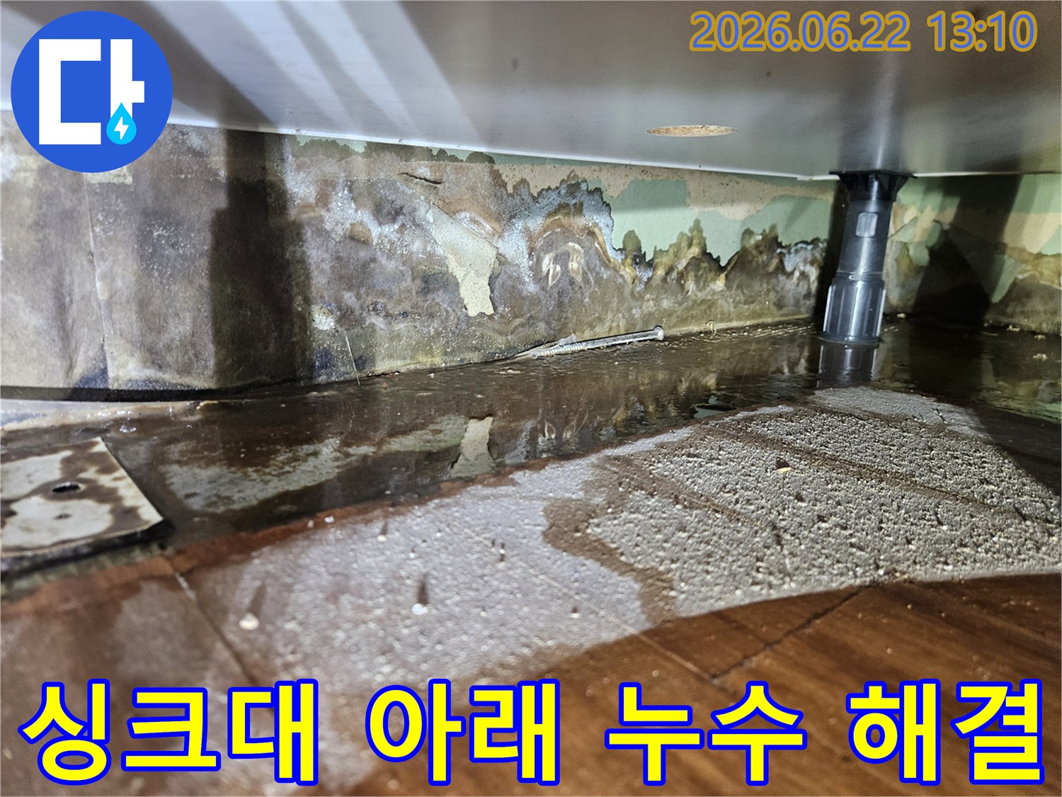 싱크대 아래에서-물이 새어 나와-벽면과 바닥이 젖고-벽지가 손상된-누수 현장-사진