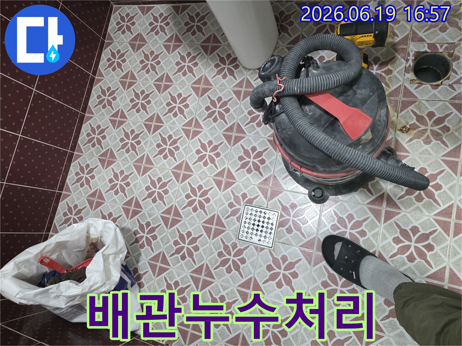 화장실 배수구 주변의-누수 처리 과정-습식 청소기로 물을 제거하고-정리된 바닥의 모습-작업자의 발과 함께