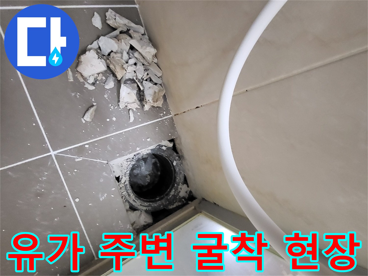 깨진 타일 조각과 드러난 하수구 배관 입구