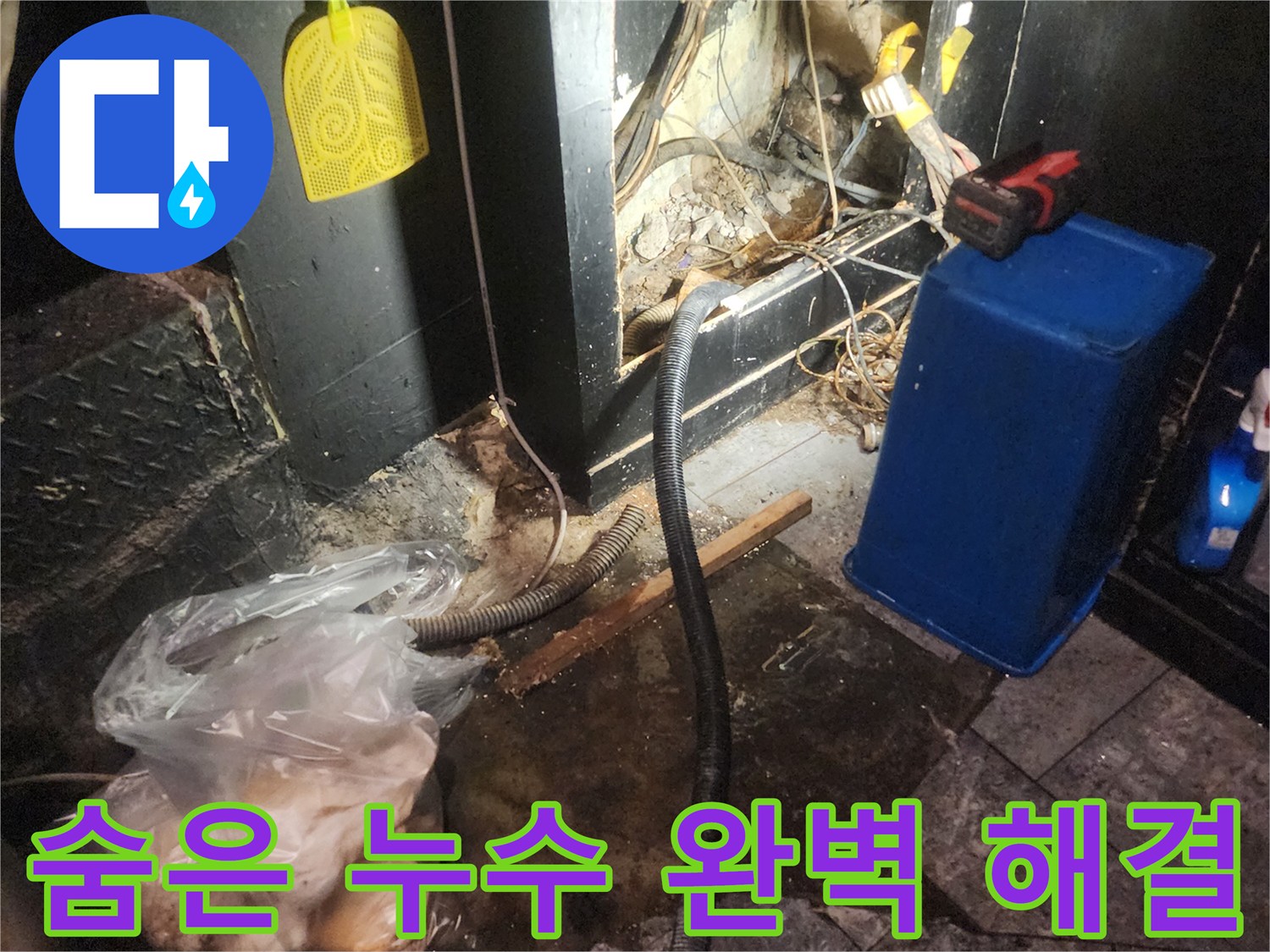 어둡고 복잡한 공간에서 숨겨진 누수 지점을 완벽하게 탐지하고 해결하기 위해 작업하는 현장-주변에는 물에 젖은 흔적과 공사 자재가 보입니다
