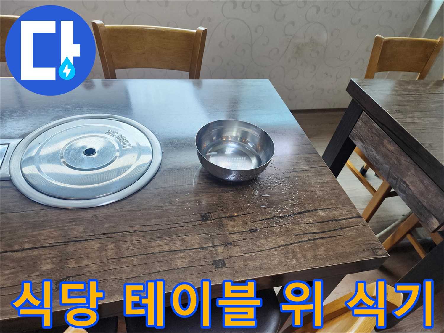 나무 재질의 식탁 위에 놓인 스테인리스 냄비와 그릇