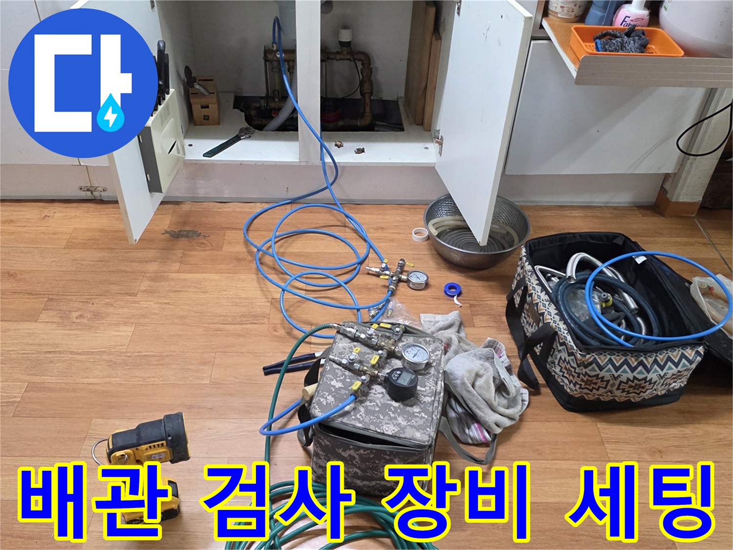 주방 하부장 근처에 배치된 누수 탐지용 전문 장비와 공압 테스트 도구