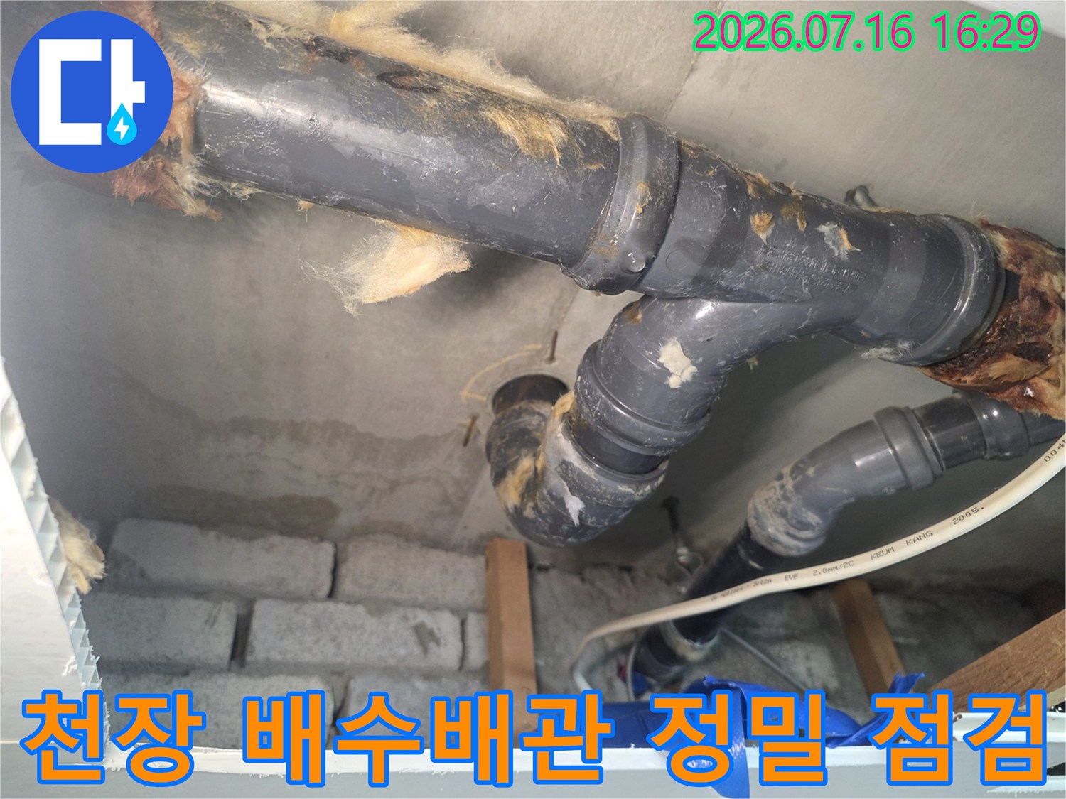 화장실 천장 내부의 노출된 하수 배관을 상세히 조사하는 모습