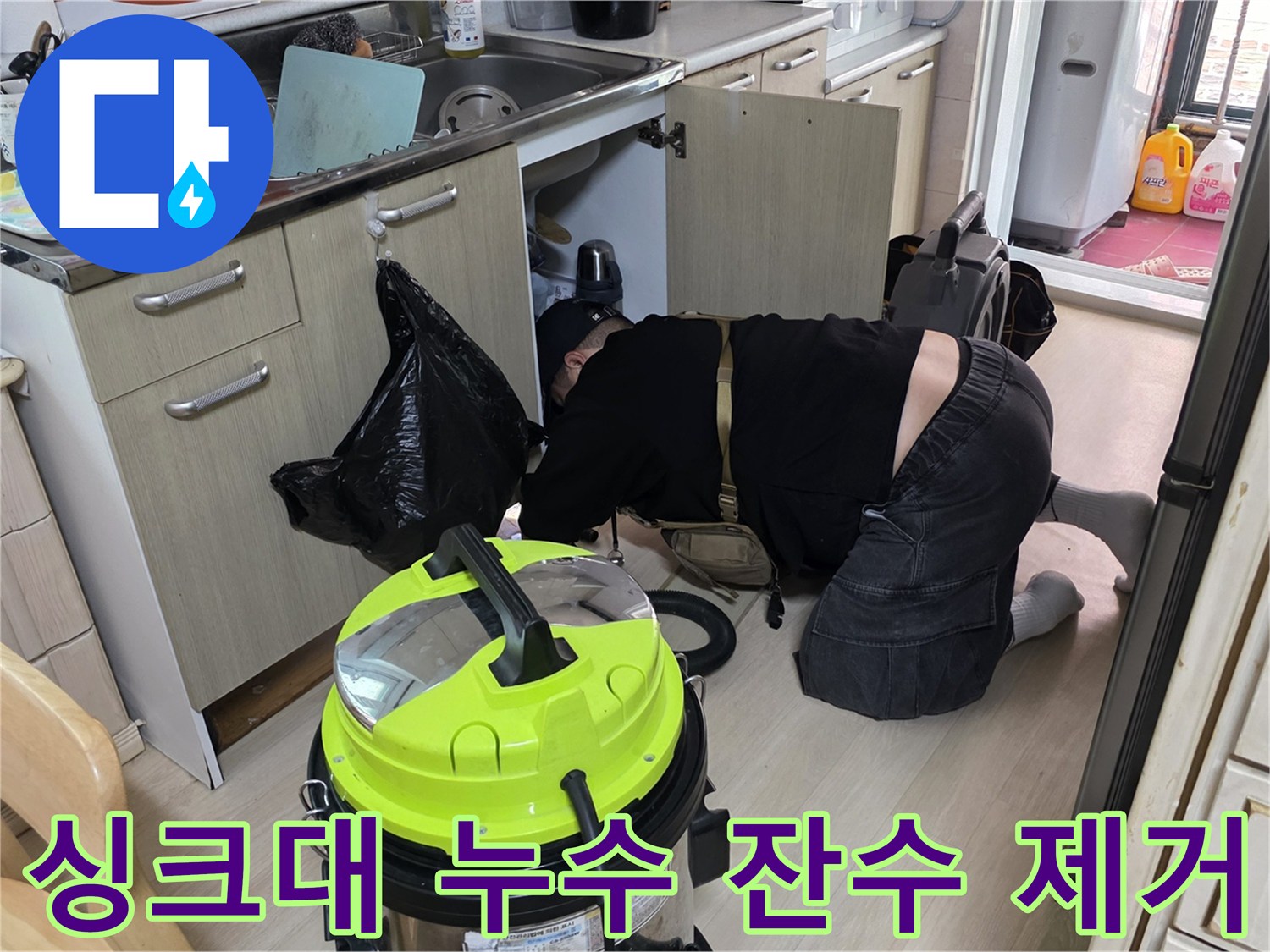 싱크대 밑 공간의 물기를 흡입하기 위해 집진기를 사용하는 모습