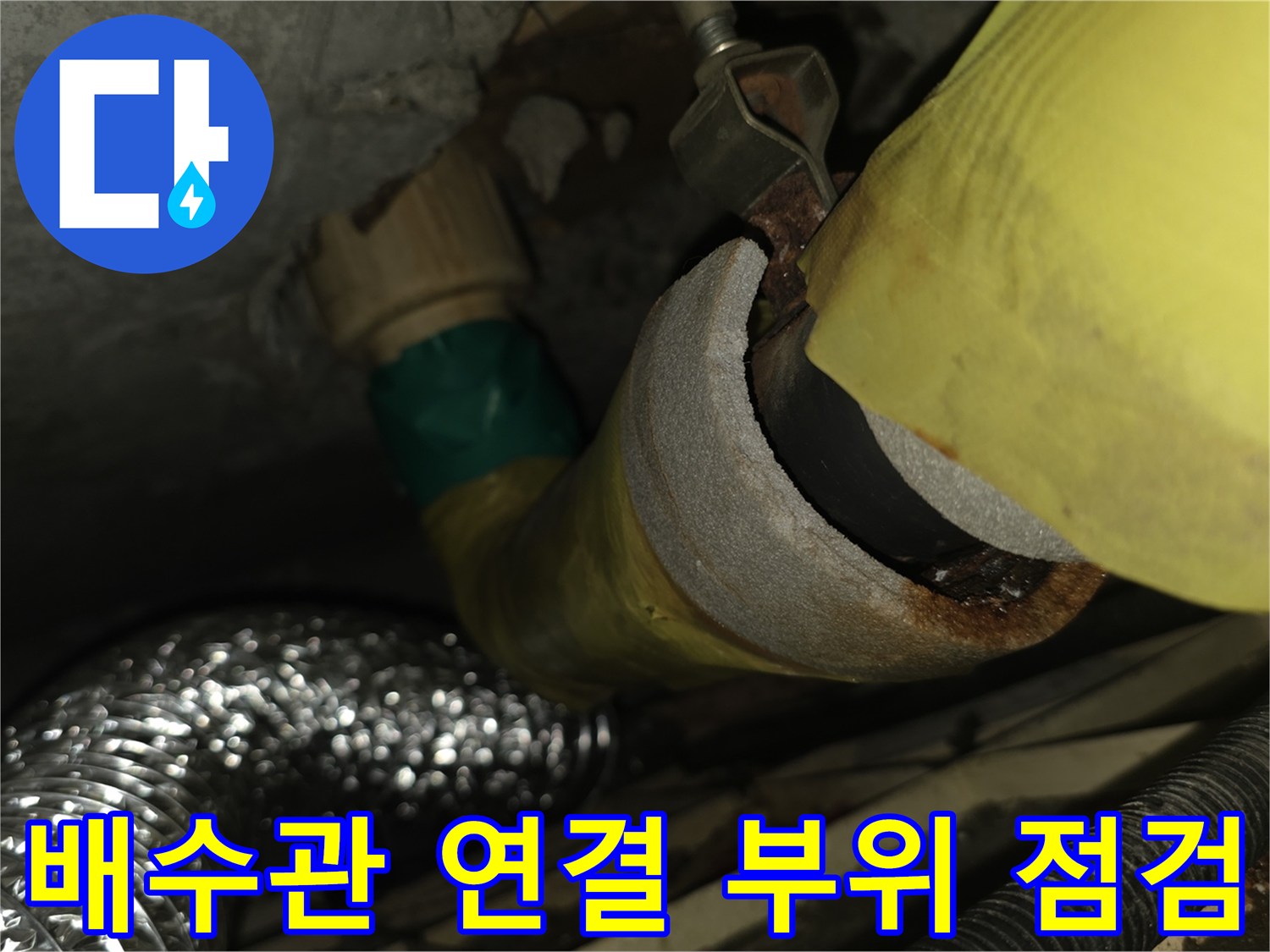 노란색 배수관과 은색 보온재가 연결된 배관 부위의 상태를 확인하는 모습