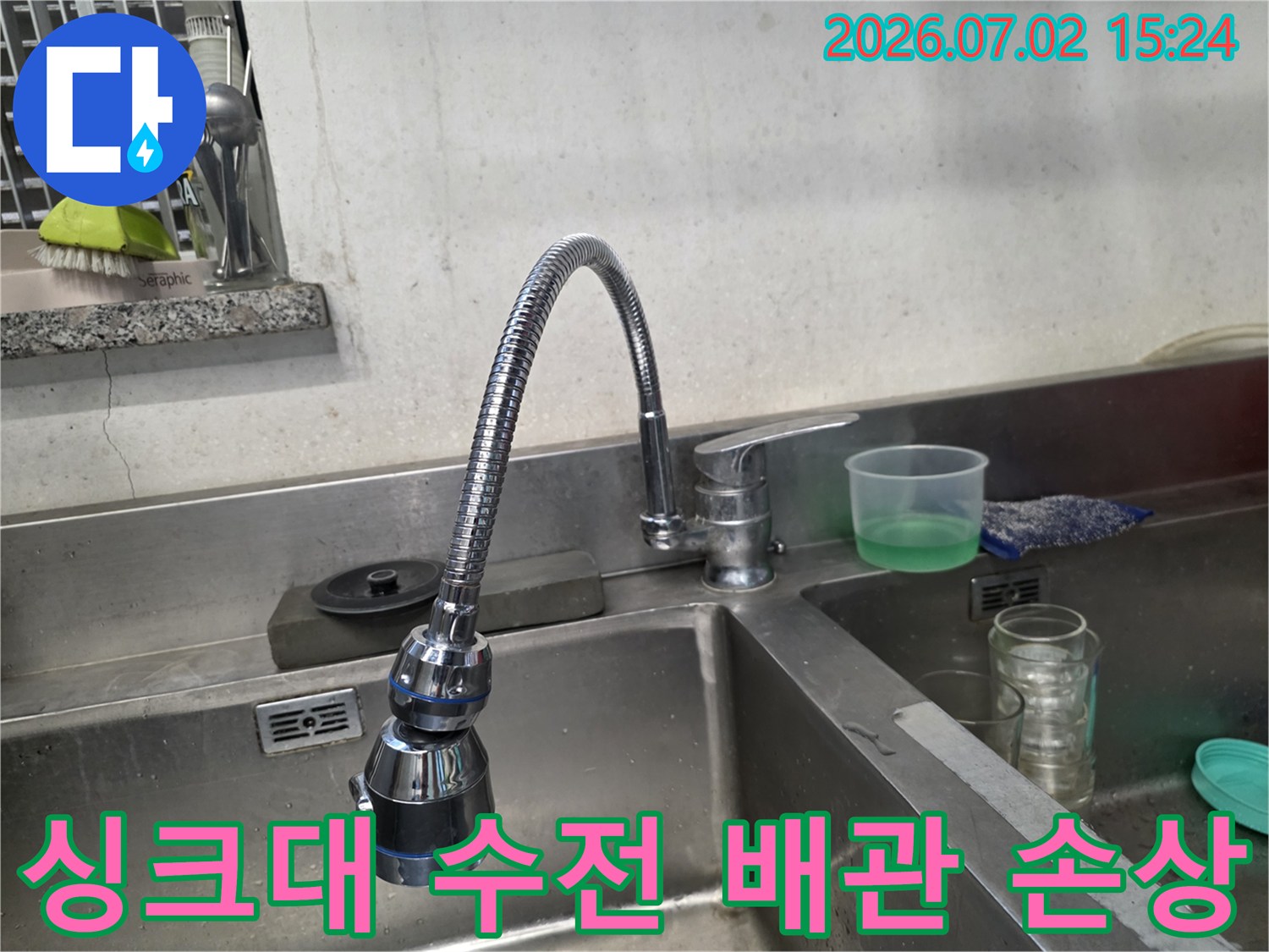 금속망이 노출된 오래된 싱크대 수전과 마모가 심한 호스가 연결된 주방 설비 모습