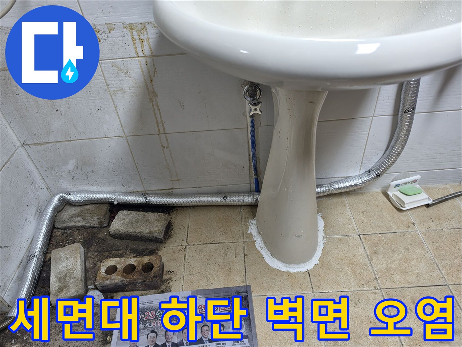 벽면 타일의 변색된 부분과 세면대 배관이 연결된 현장 사진입니다.