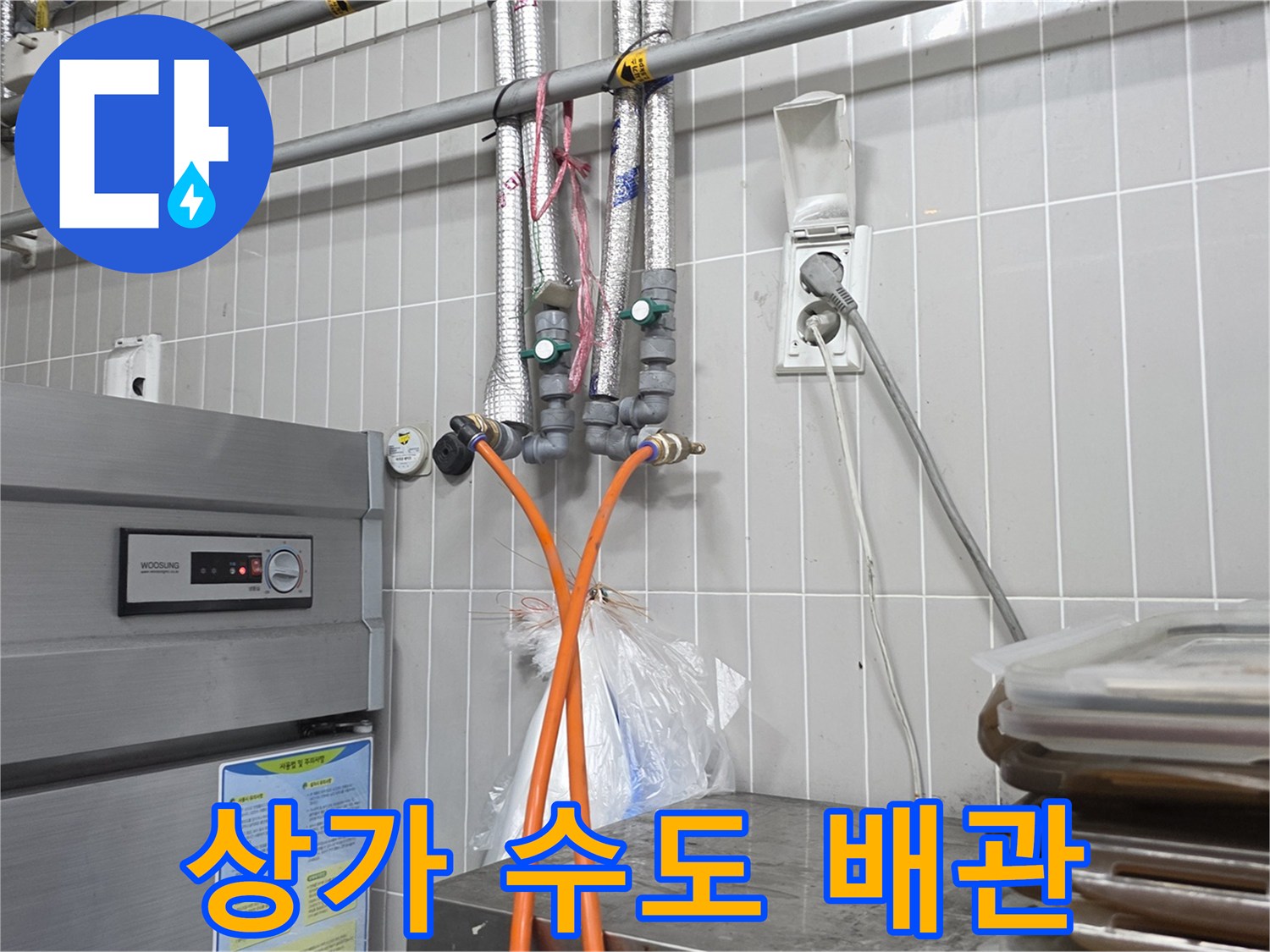 벽면에 고정된 은색 배관과 주황색 호스 연결부