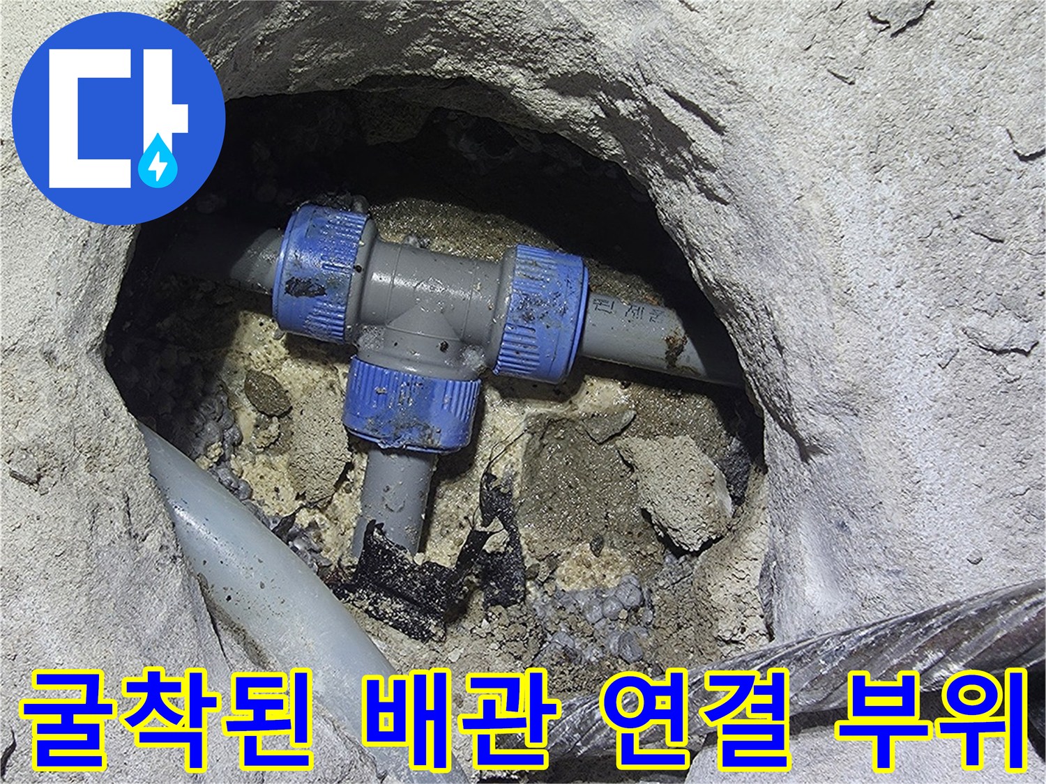 콘크리트 굴착 부위-노출된 파란색 배관 부속과 수선 중인 현장 모습