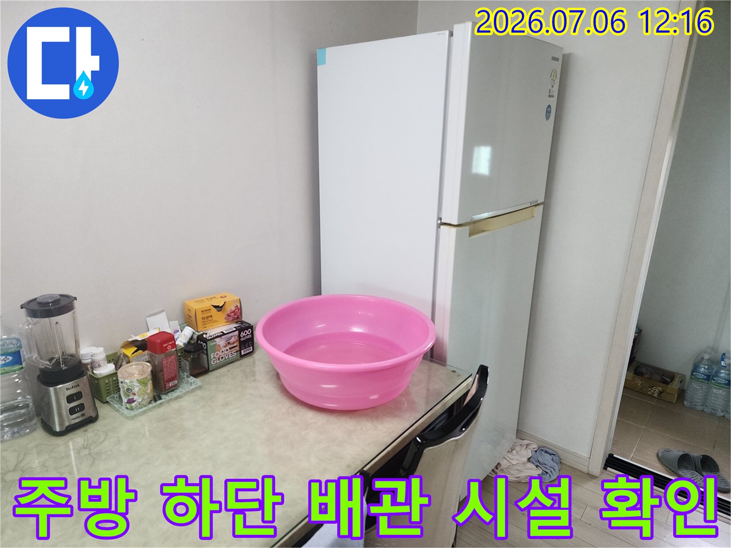 싱크대 밑에 놓인 분홍색 대야와 주변 소품을 배경으로 한 배출부 점검 현장