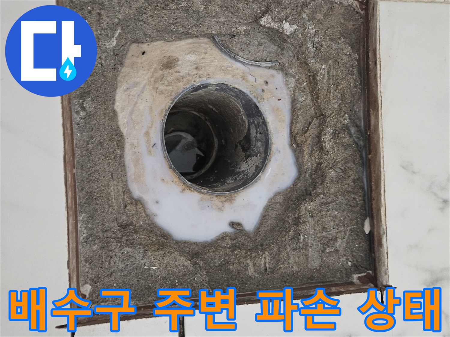 화장실 배수구 주변의 타일과 시멘트가 제거되어 배관이 노출된 모습
