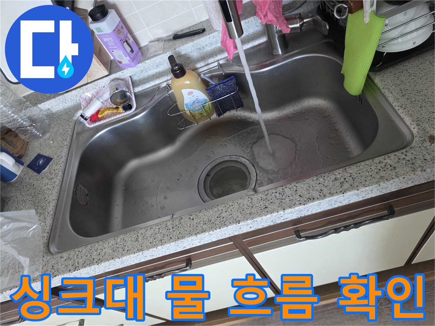 스테인리스 싱크대에 물을 틀어 배수 상태를 점검하는 모습