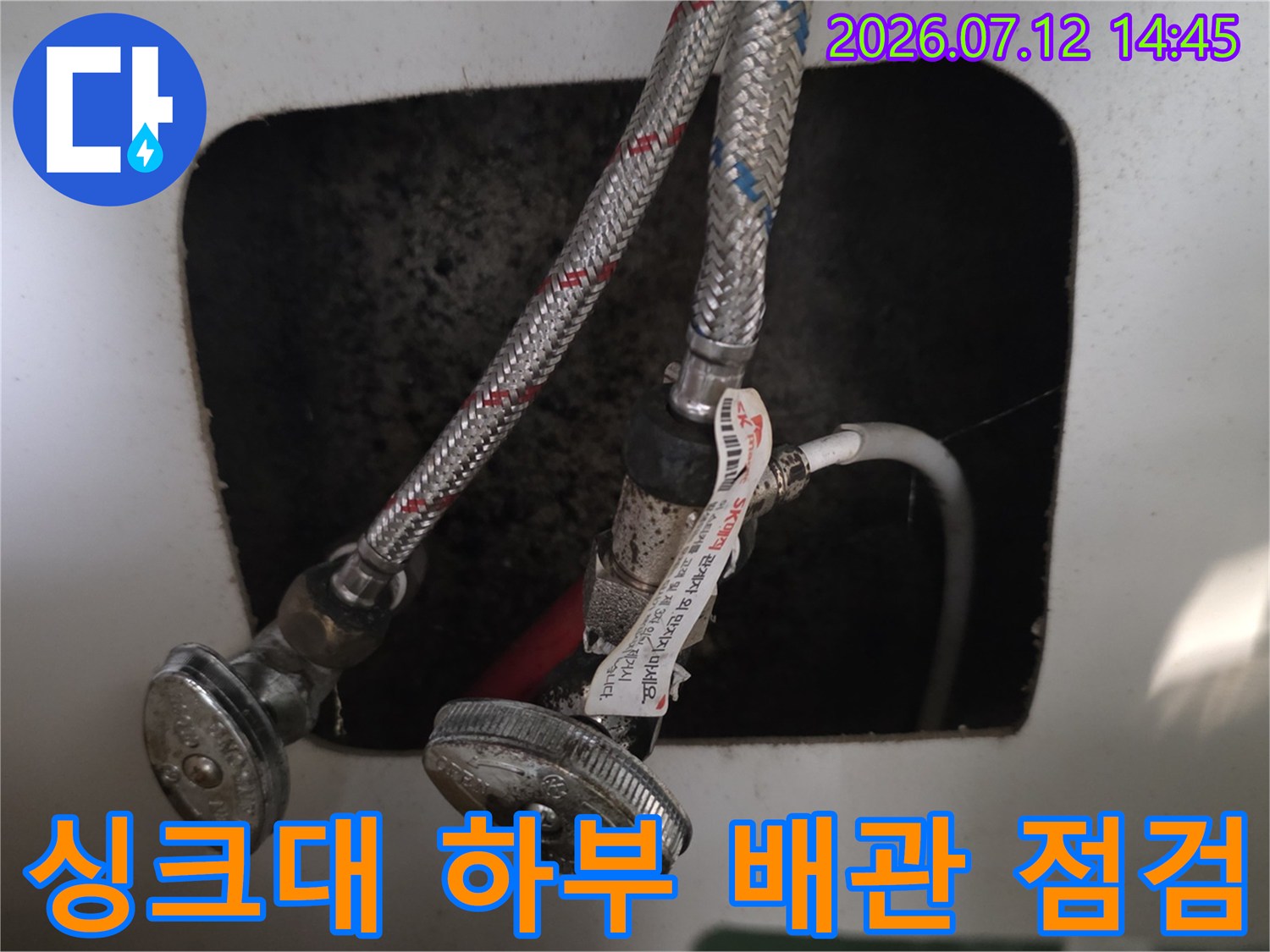 싱크대 아래쪽 노출된 배관과 연결 부위를 상세히 점검하는 모습