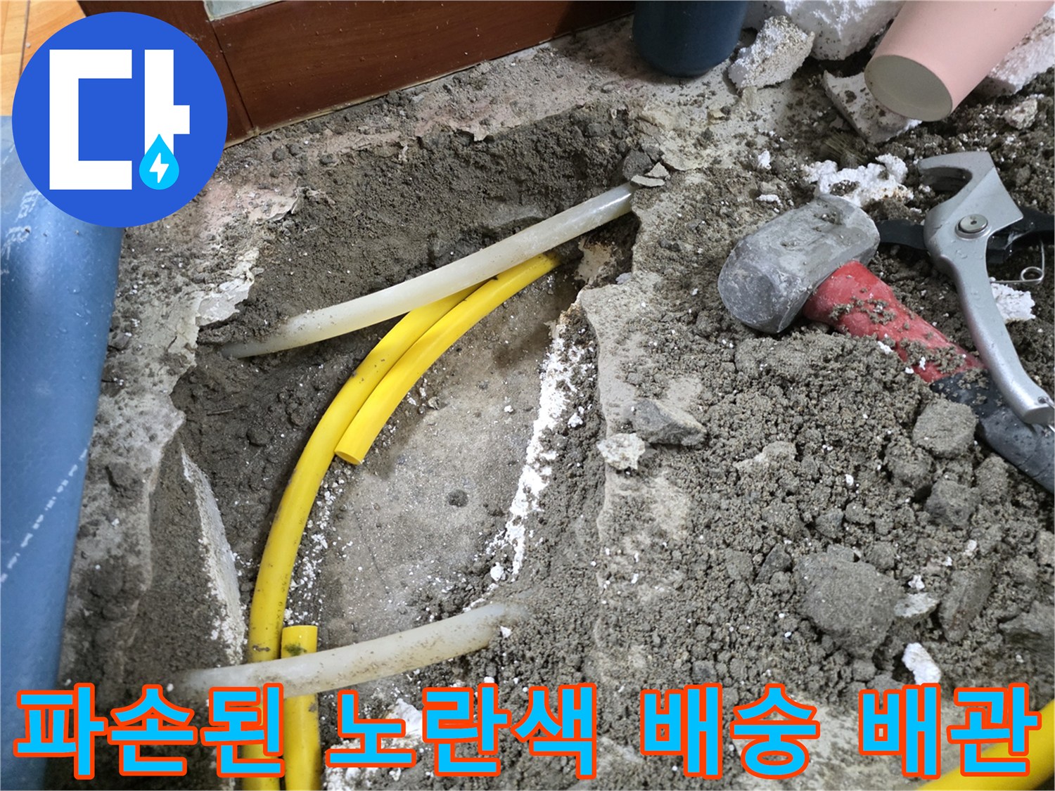 바닥 흙 속에 드러난 파손된 노란색 배관과 공사 도구들