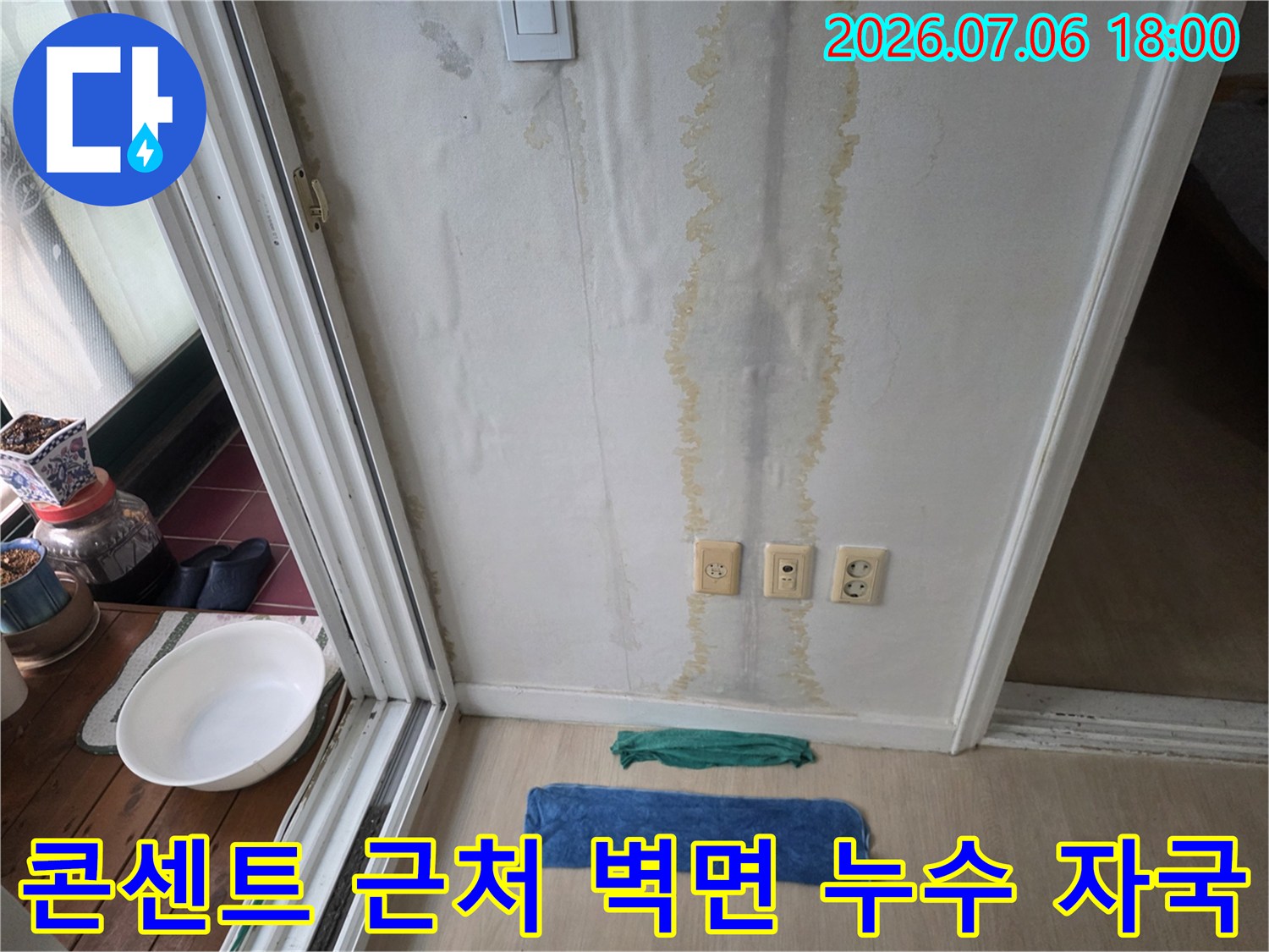 벽면에 수직으로 번진 노란색 물자국과 하단부의 콘센트 부근 모습