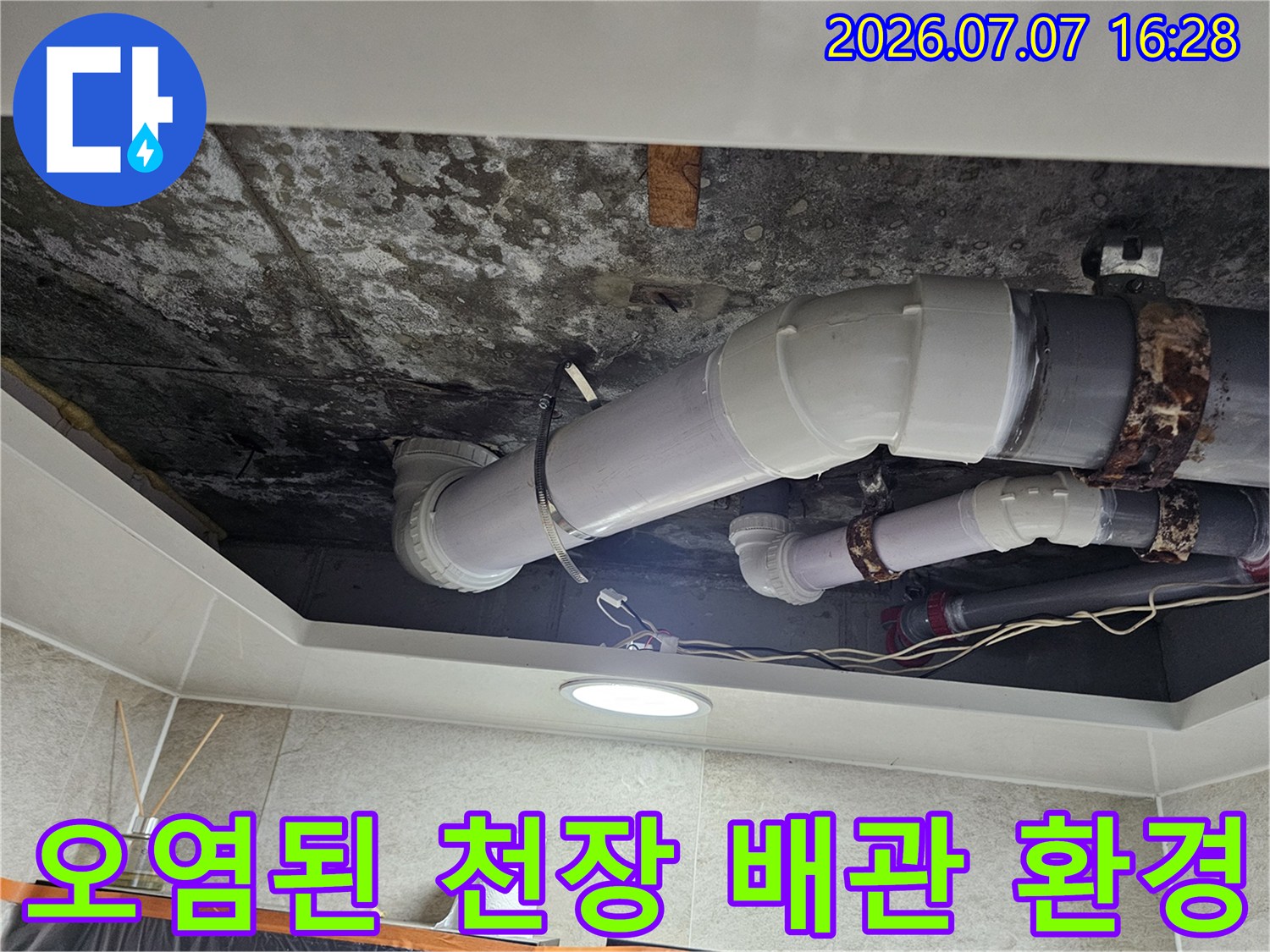 습기로 인해 오염된 천장 내부 공간과 노출된 배관 시스템