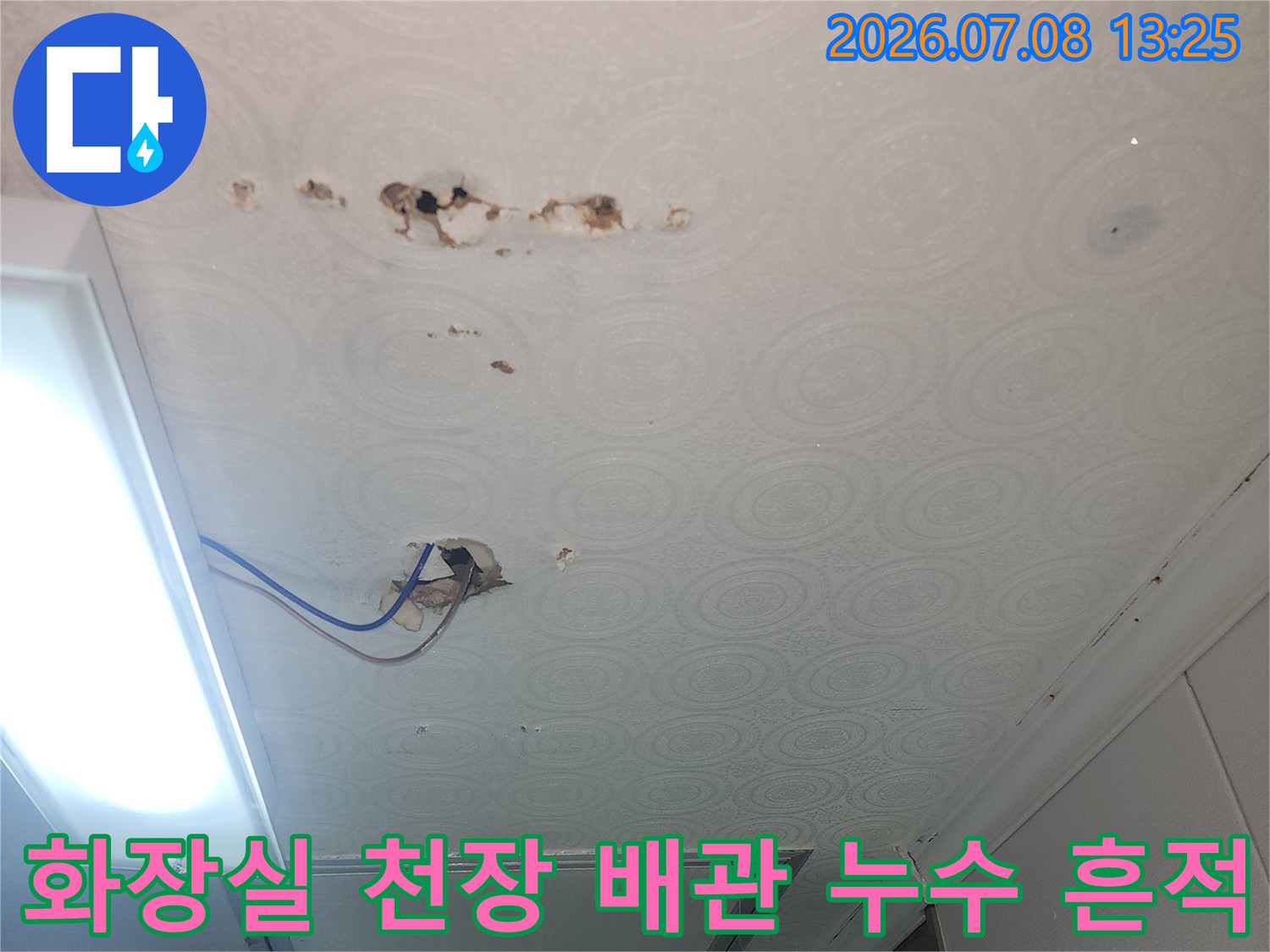 화장실 천장 벽지에 누수 피해가 발생한 모습과 노출된 하수 배관 부위
