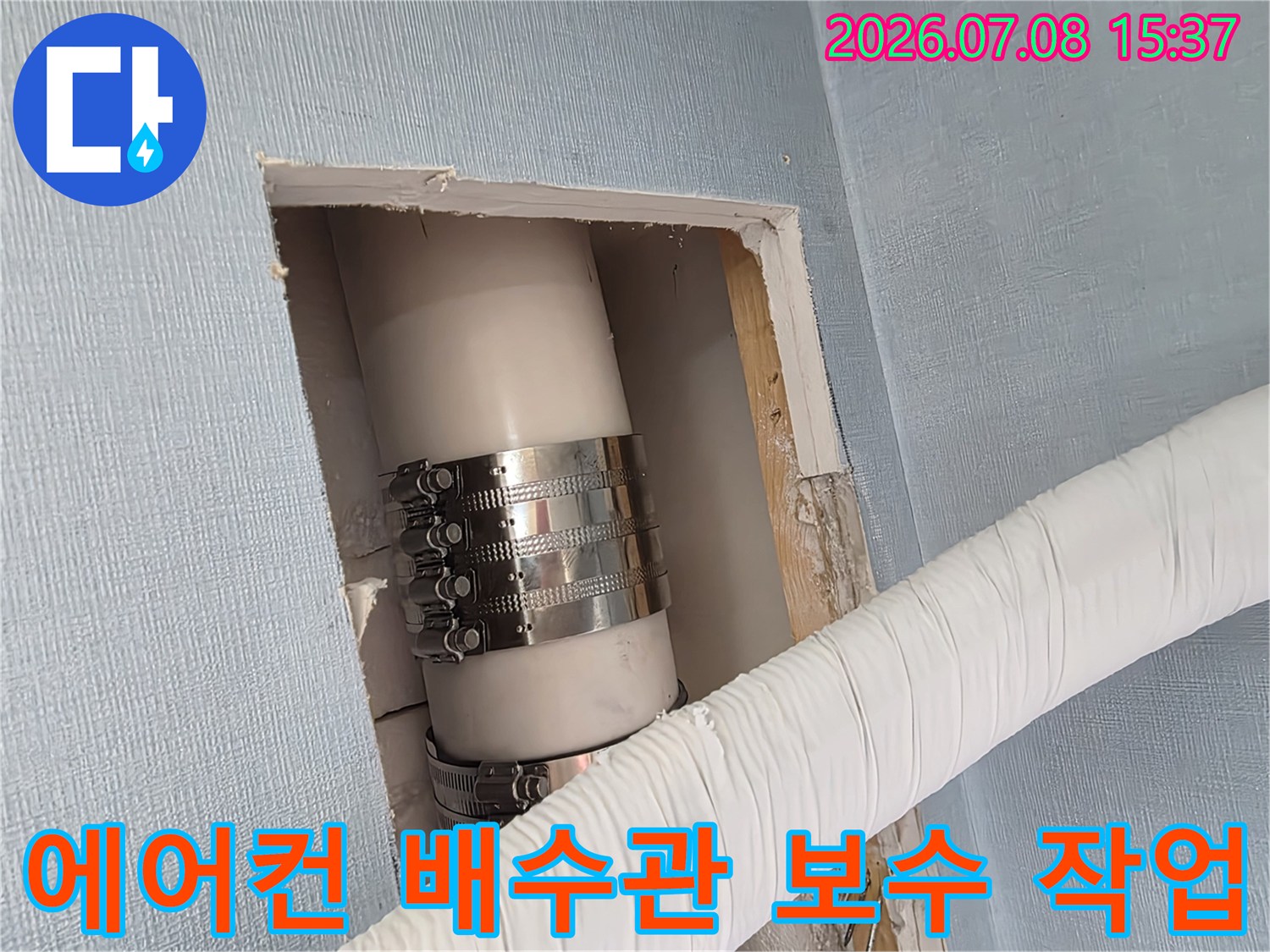 금속 밴드로 고정된 에어컨 배수관의 연결 부위 점검 모습