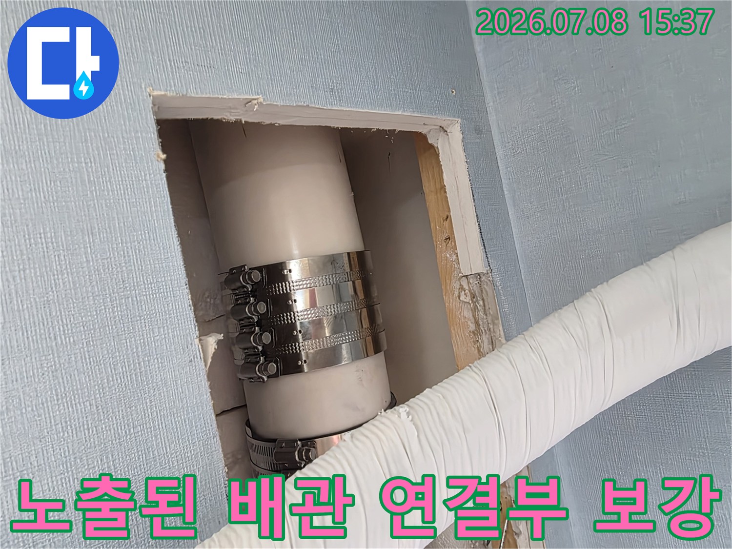 금속 밴드로 단단히 고정된 흰색 배수관과 하얀 테이핑으로 보호된 외부 배관의 모습