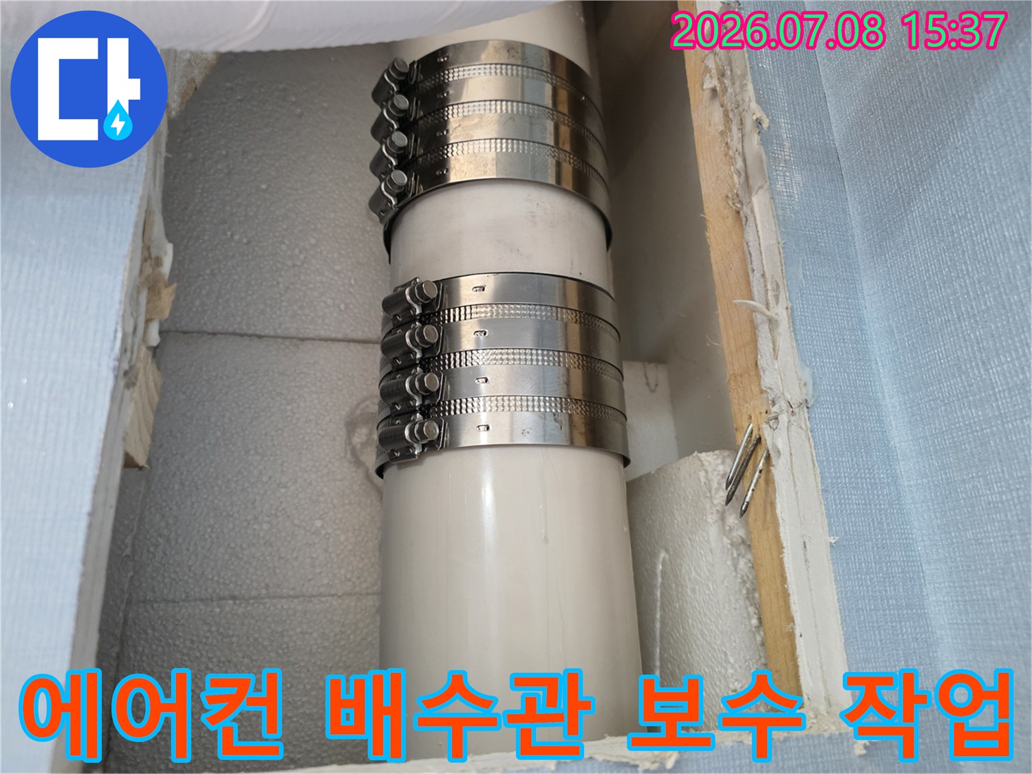 금속 클램프로 고정된 에어컨 드레인 배관의 수리 현장 사진