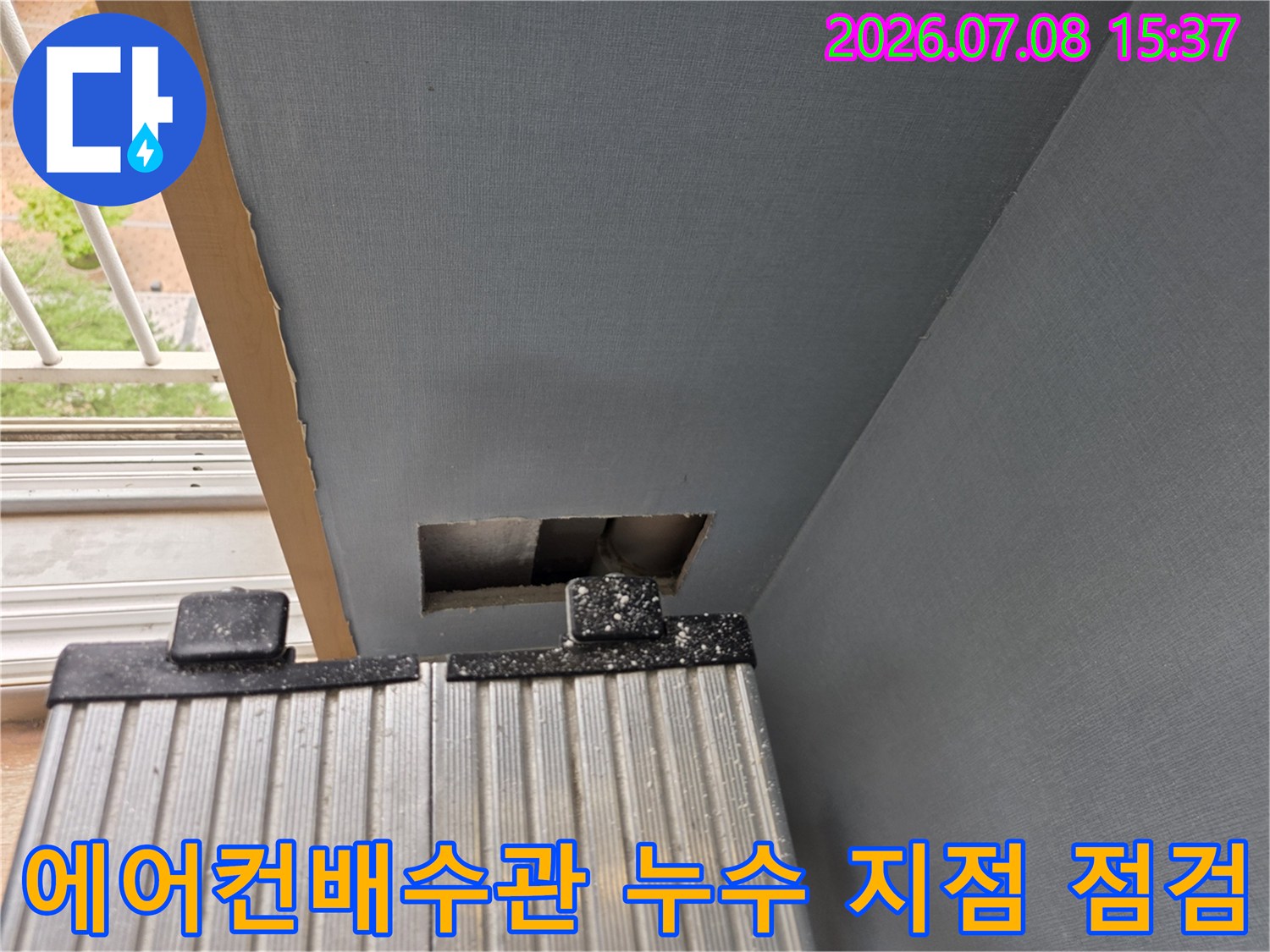 벽면을 절개하여 노출된 에어컨 배수용 드레인 호스의 연결 부위를 세밀하게 점검하는 모습