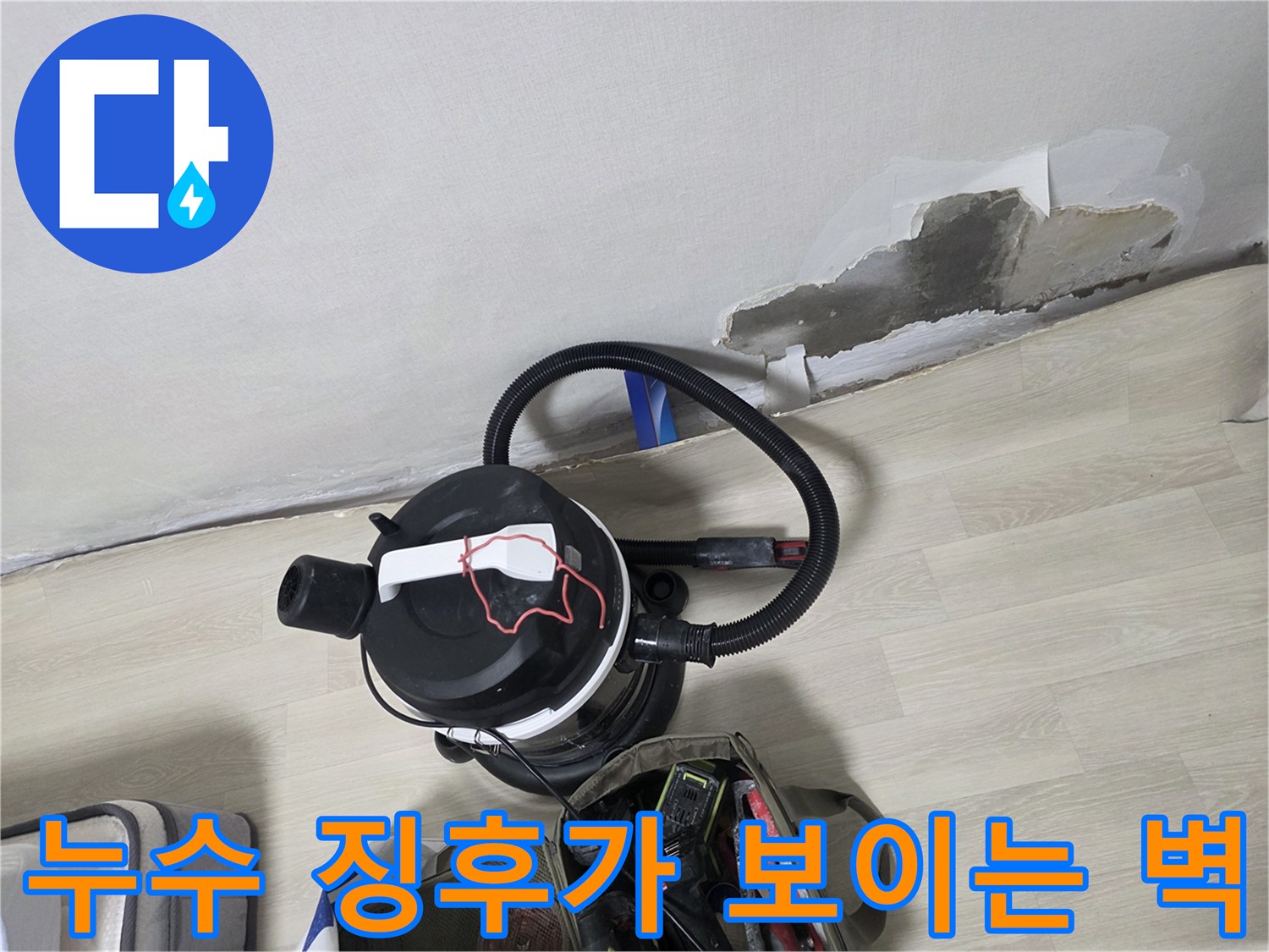 훼손된 벽지와 작업용 청소기 배치