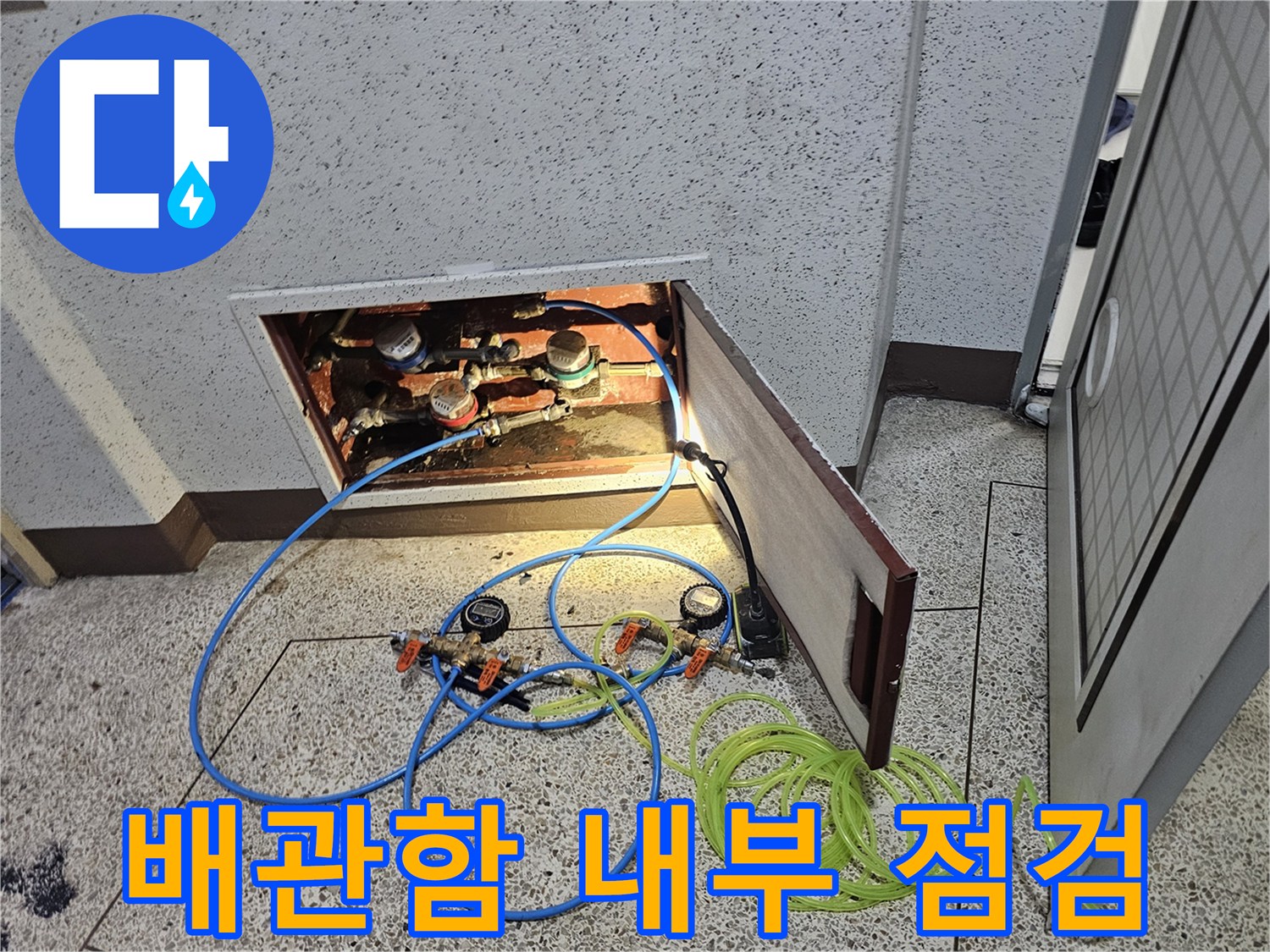 아파트 베란다 배관함 내부의 복잡한 배관과 압력 테스트 장비 모습