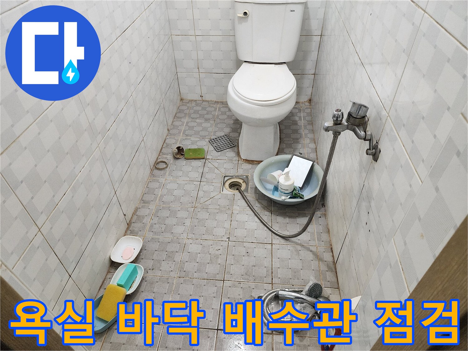 변기 뒤쪽 배수구 주변의 타일과 배관 상태를 보여주는 사진입니다.
