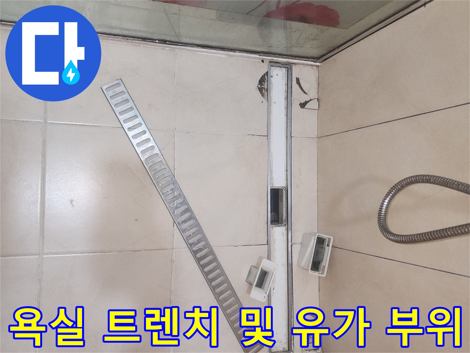 화장실 배수구 주변의 금속 트렌치와 타일 마감 상태