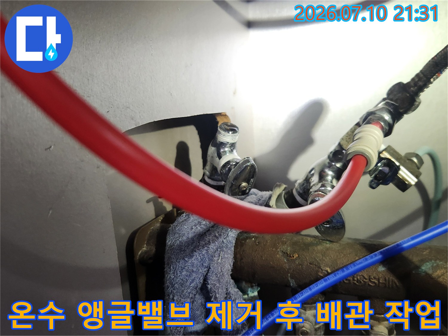 빨간색 온수 호스와 금속 배관이 연결된 지점의 보수 공사 장면