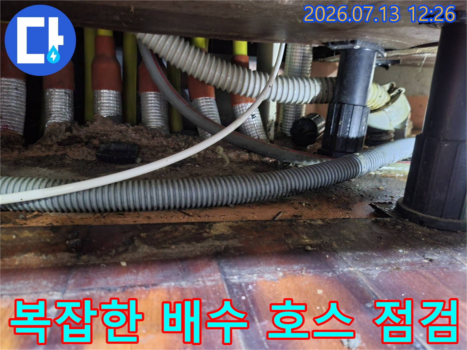 싱크대 밑에 얽혀있는 회색 배수관과 노출된 배관 시스템