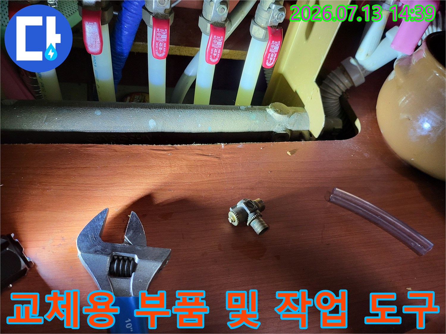T자형-금속-부속과-투명한-연결-호스-그리고-몽키스패너가-나란히-놓인-모습