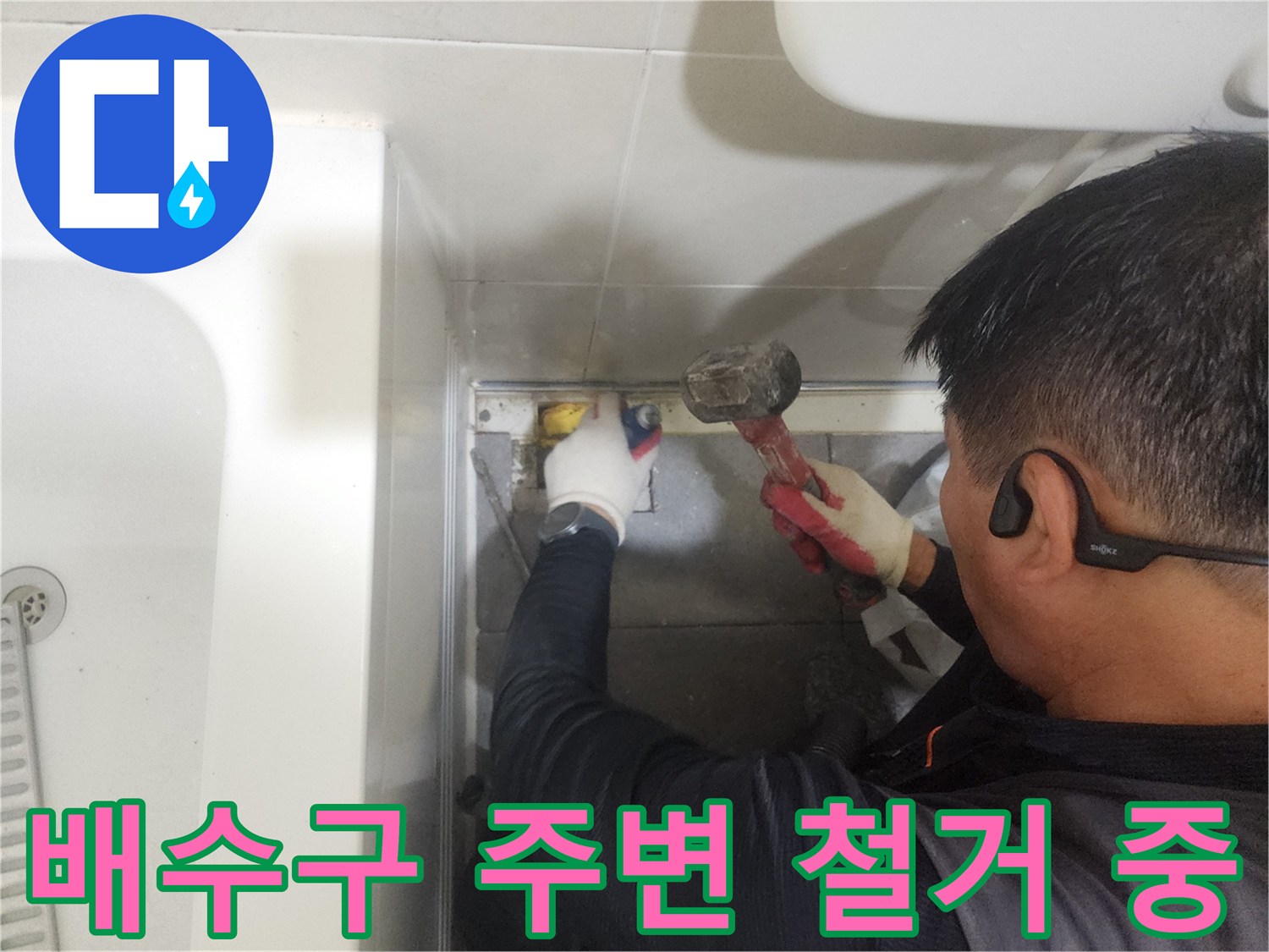 망치를 이용해 욕실 배수구 주변 타일 마감재를 제거하는 모습