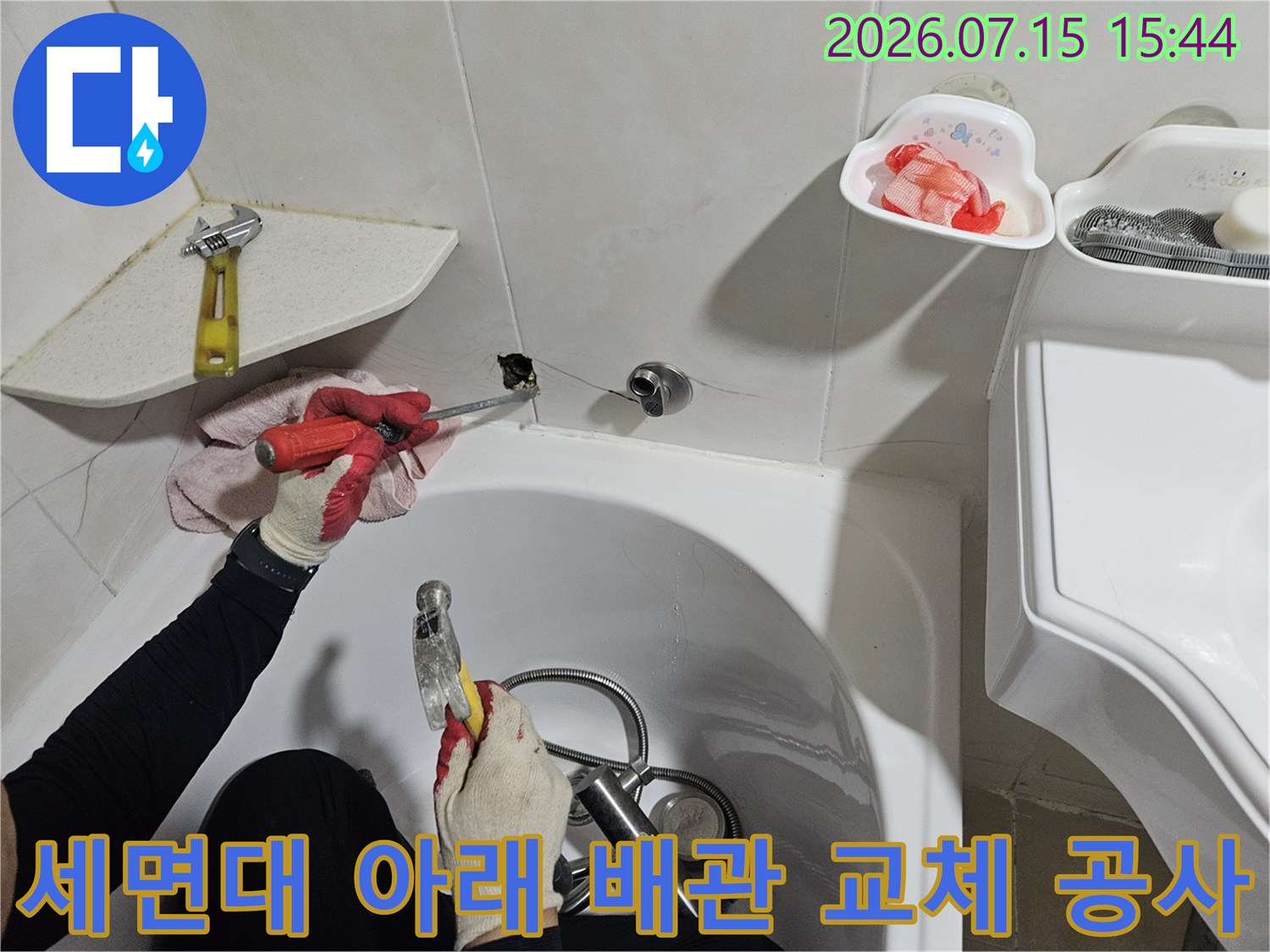 작업자가 세면대 하단에서 누수가 발생한 노후 배관을 수리하는 전문적인 모습