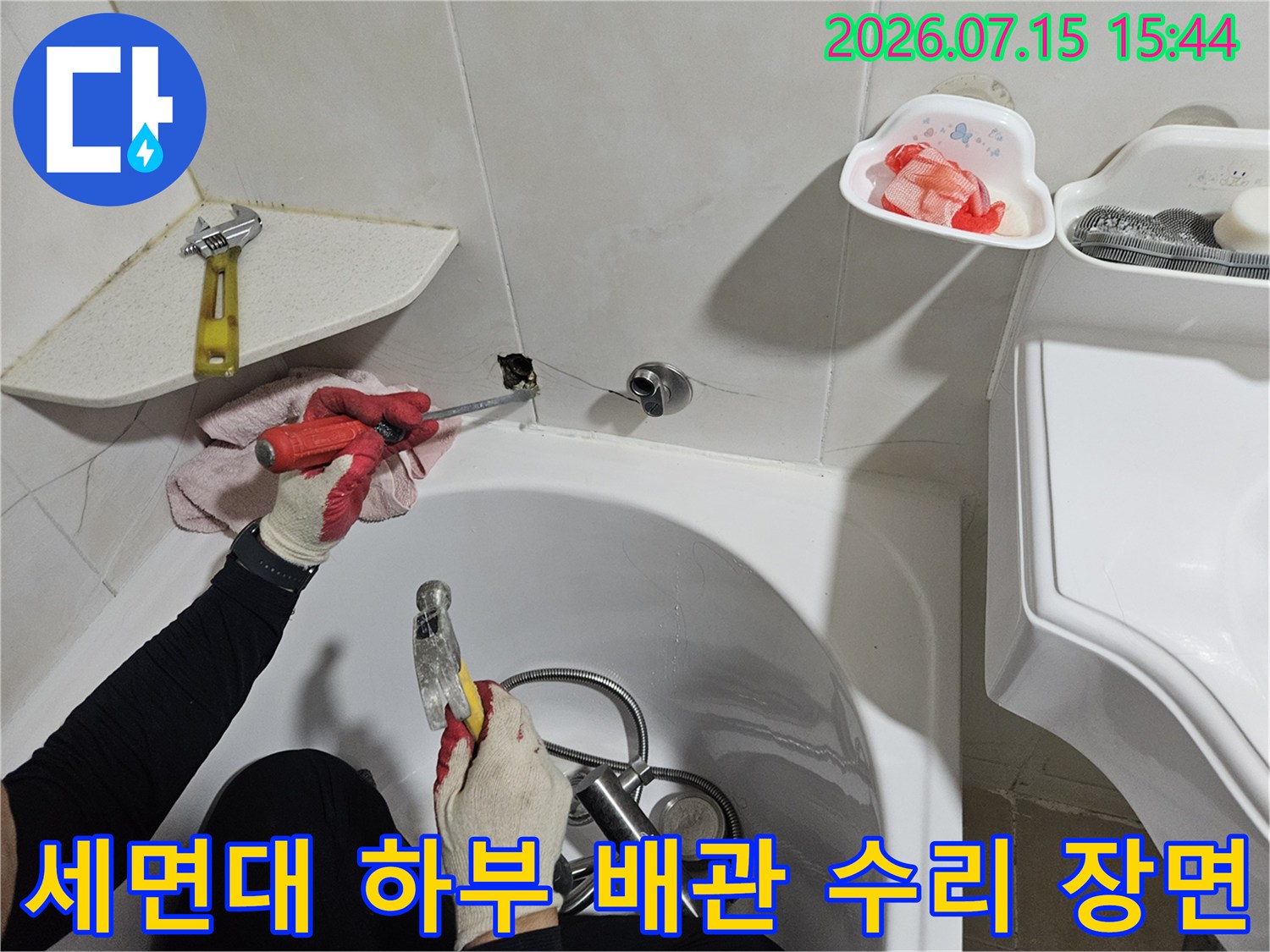 장갑을 끼고 세면대 아래쪽 누수된 배관 부위를 정밀하게 수리하는 작업 현장
