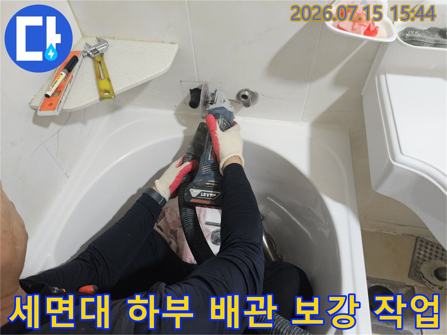 전문가가 좁은 세면대 아래 공간에서 누수된 온수 배관을 교체하는 현장 모습