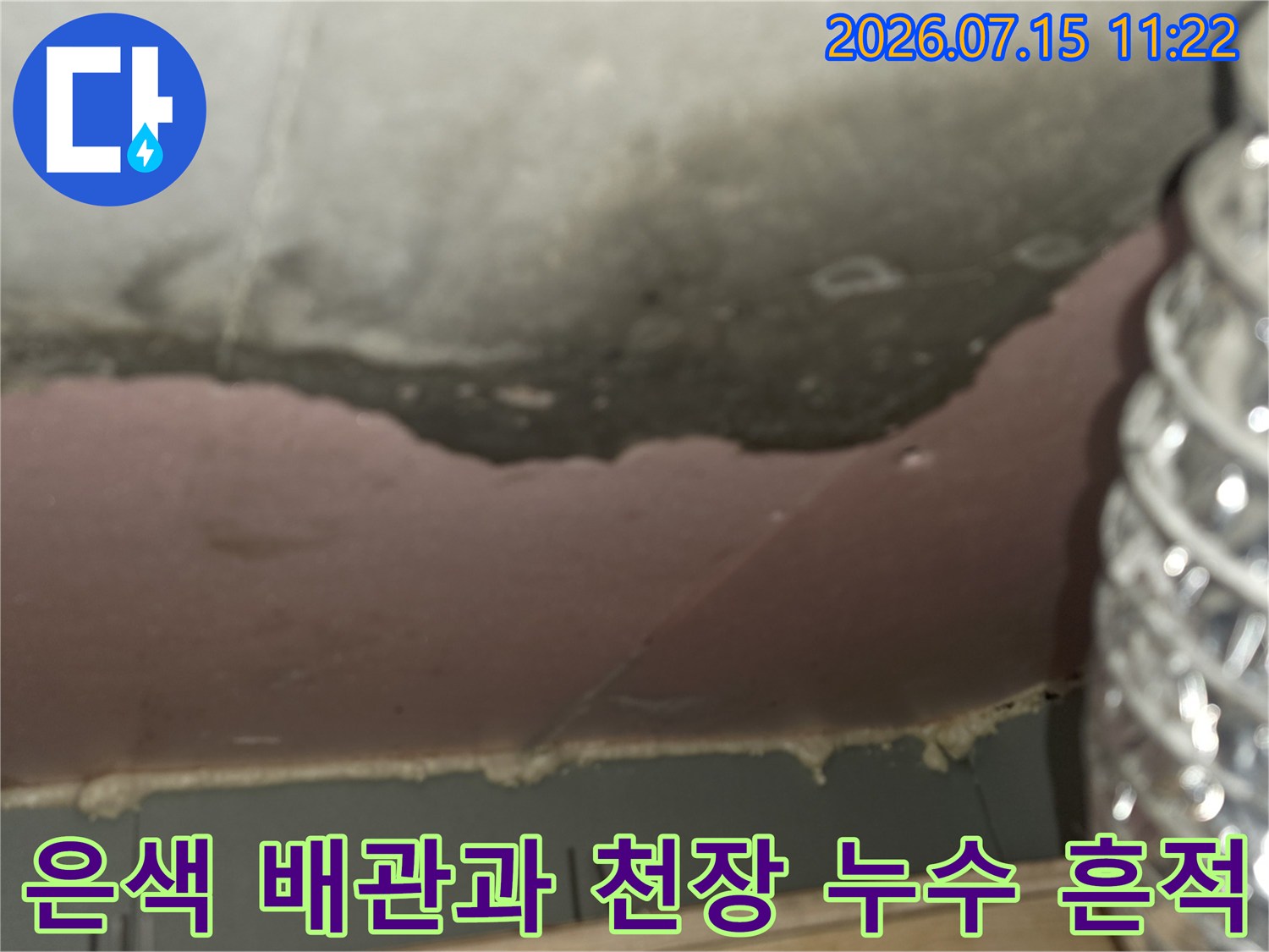 천장의 짙은 오염 부위-우측에 설치된 은색의 주름진 배관 모습