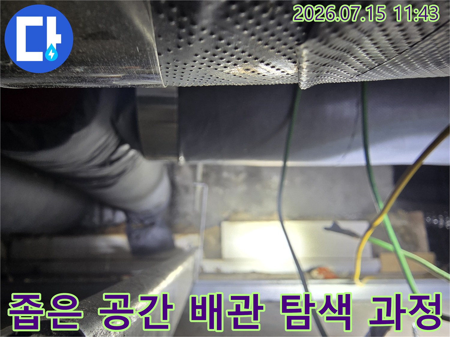 천장 내부의-어두운 공간에서 보온재로 마감된 두꺼운 배관을-살펴보고 있는 모습