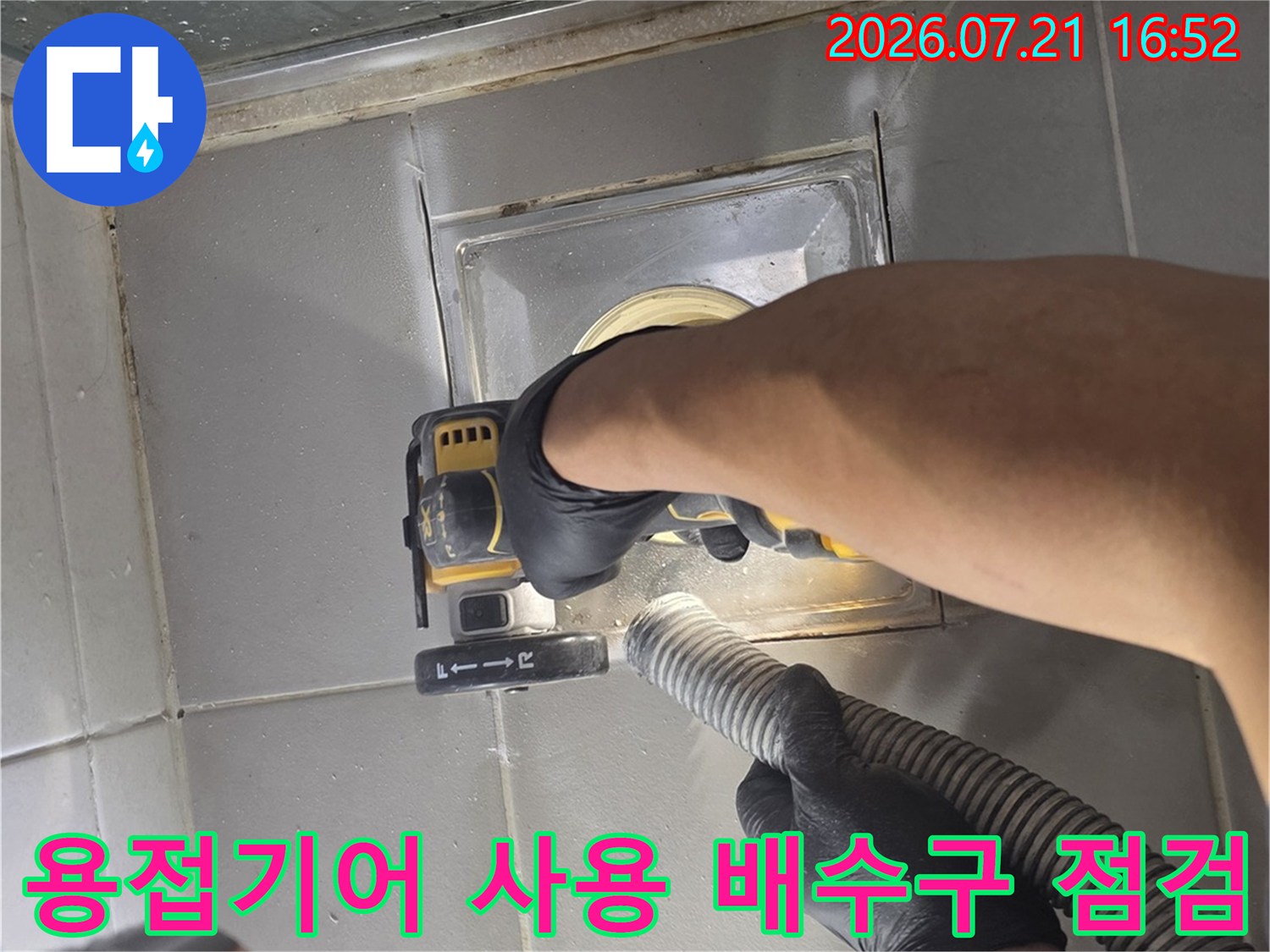 작업자가 파란색 전동공구를 사용하여 욕실 바닥 배수구 부근을 정밀하게 점검하는 모습