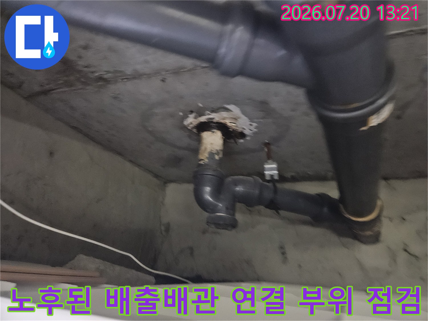 먼지나 이물질이 낀 노후된 세탁실 배수관과 벽면 관통부의 상세 모습