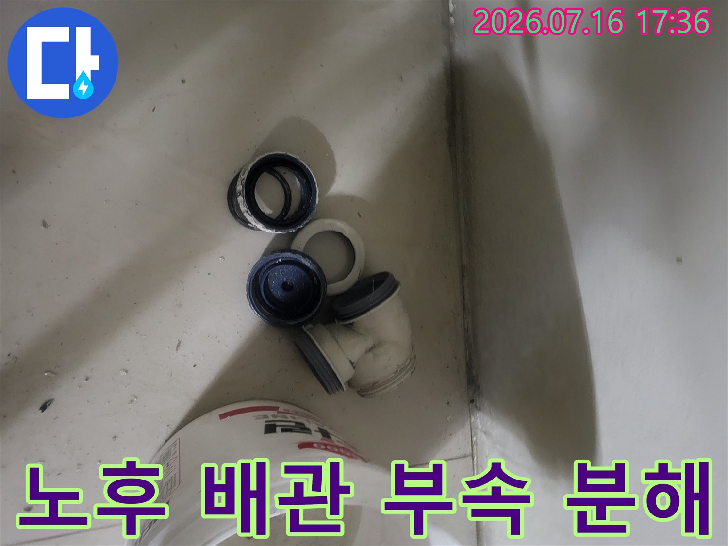 바닥에 놓인 파손된 배관 소켓과 트랩-교체 전 상세 점검 단계