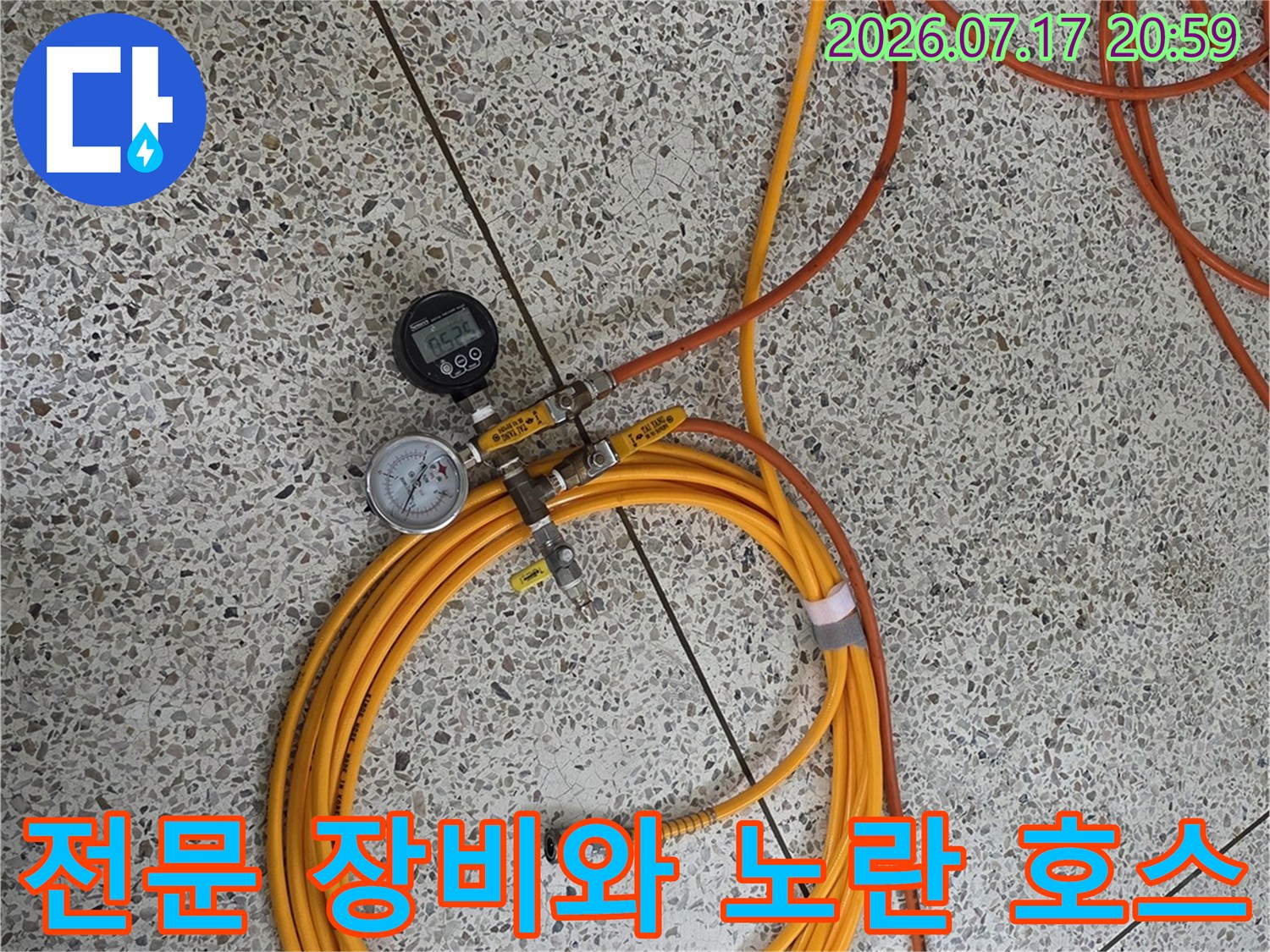 두 개의 게이지가 연결된 공압 테스트 시스템과 길게 늘어진 노란색 호스