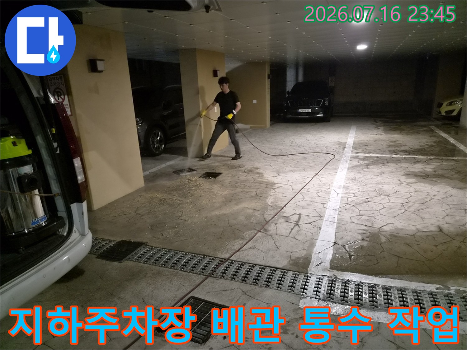 지하 주차장에서 고압 세척 장비를 사용하여 배관 내 이물질을 제거하는 장면