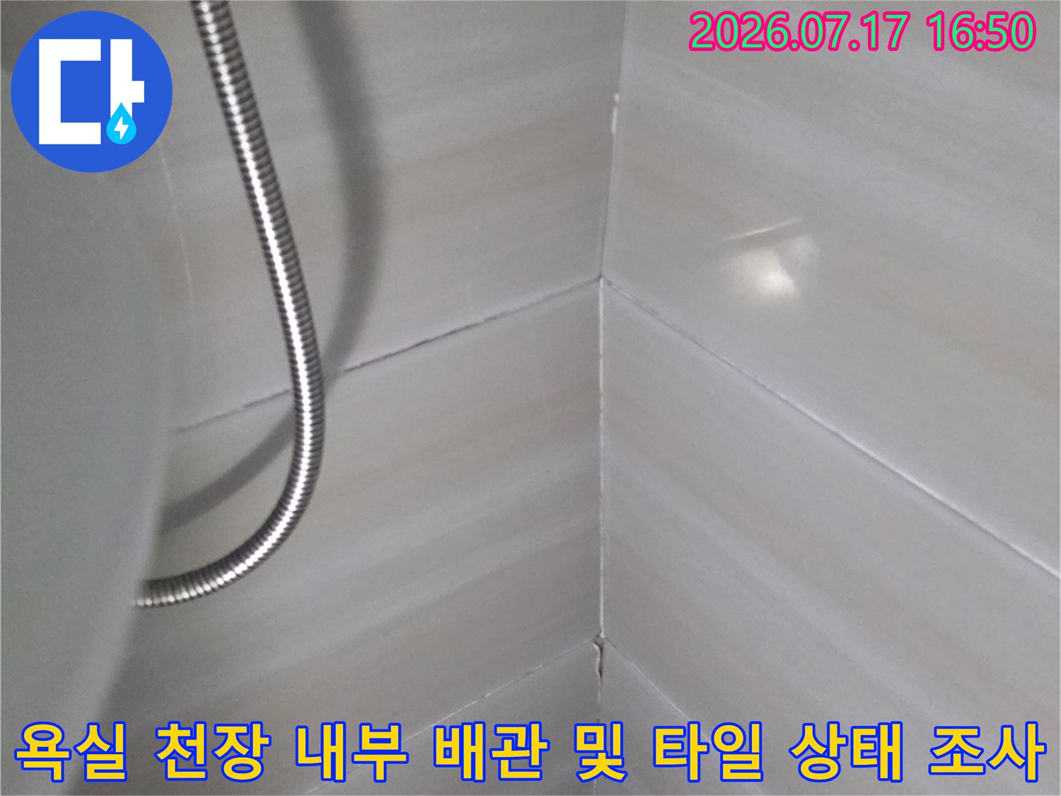흰색 타일로 마감된 욕실 천장과 금속 소재의 유연한 관-정면샷