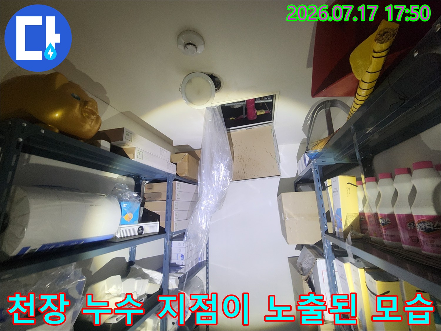 열린 천장의 사각 구멍-그 내부의 배관들과 주변 적재 선반들