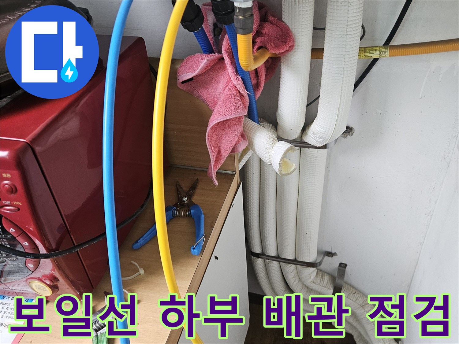 보일러 아래쪽의 노란색과 파란색 호스가 얽혀 있는 배관 구조입니다.